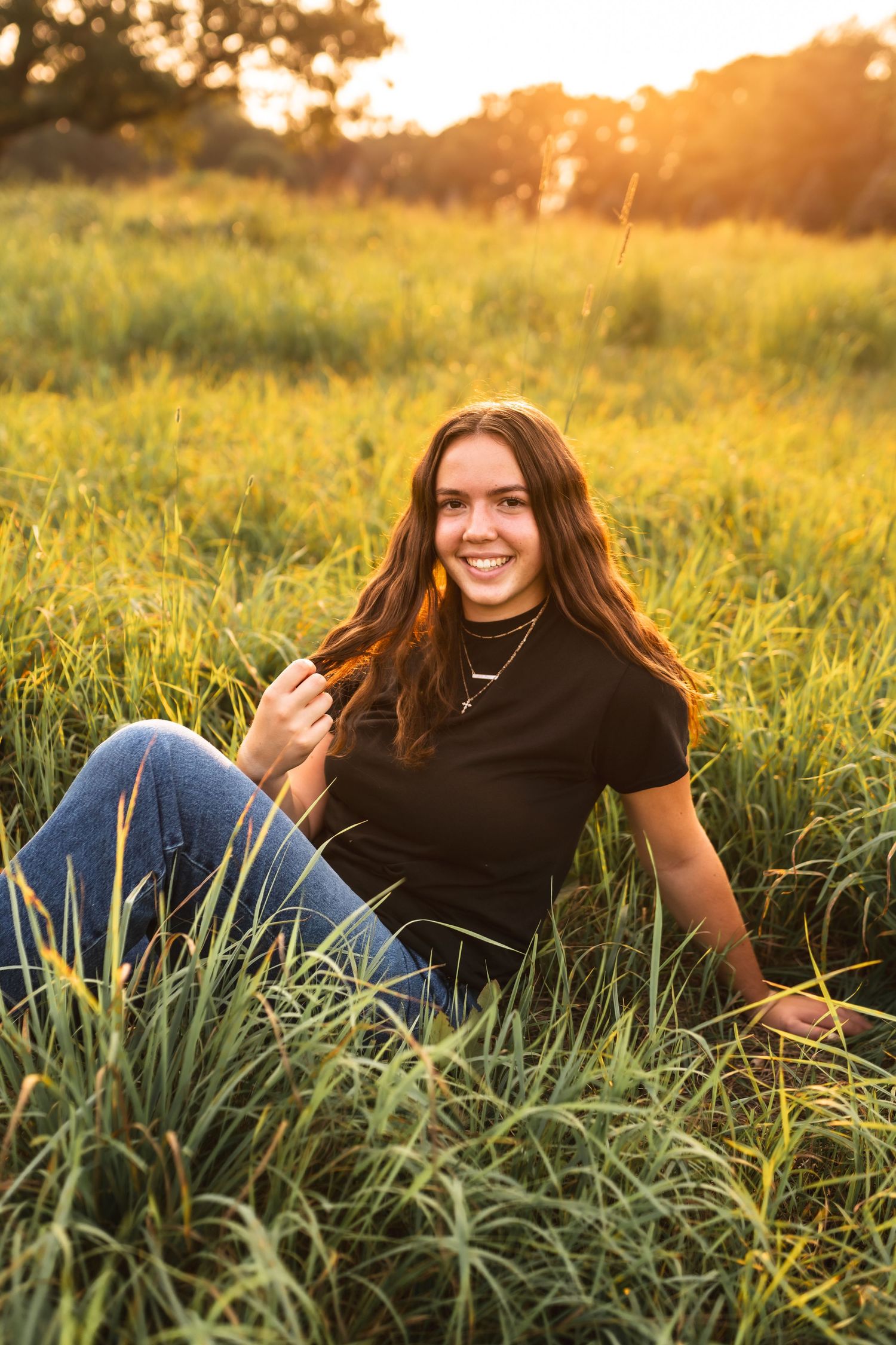 Picture of a senior girl posing in a field during golden hour.