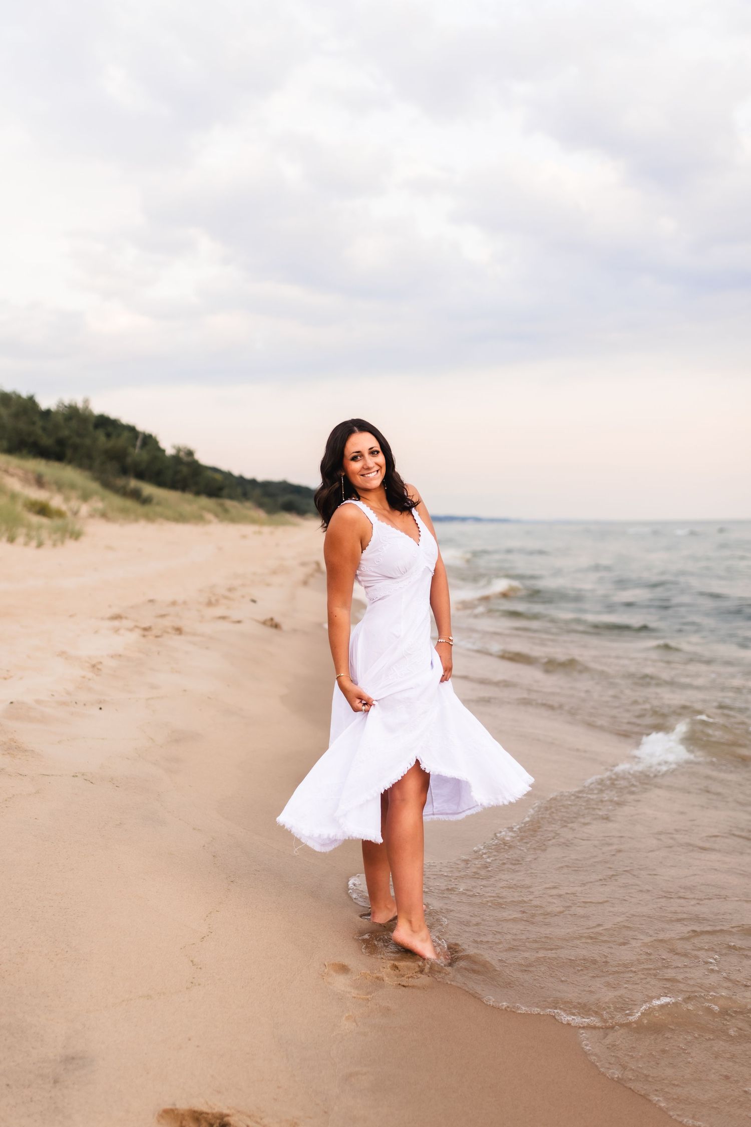 A senior girl with a flowing white dress on the beach at PJ Hoffmaster State Park.