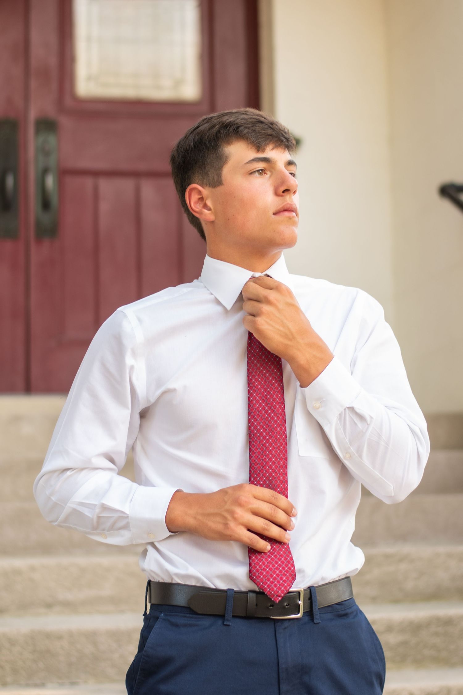 A senior portrait of a high school senior fixing his tie in downtown Ionia Michigan.