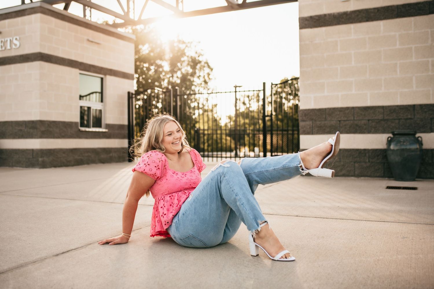 Senior girl posing in her heals with the sun beaming down behind her.