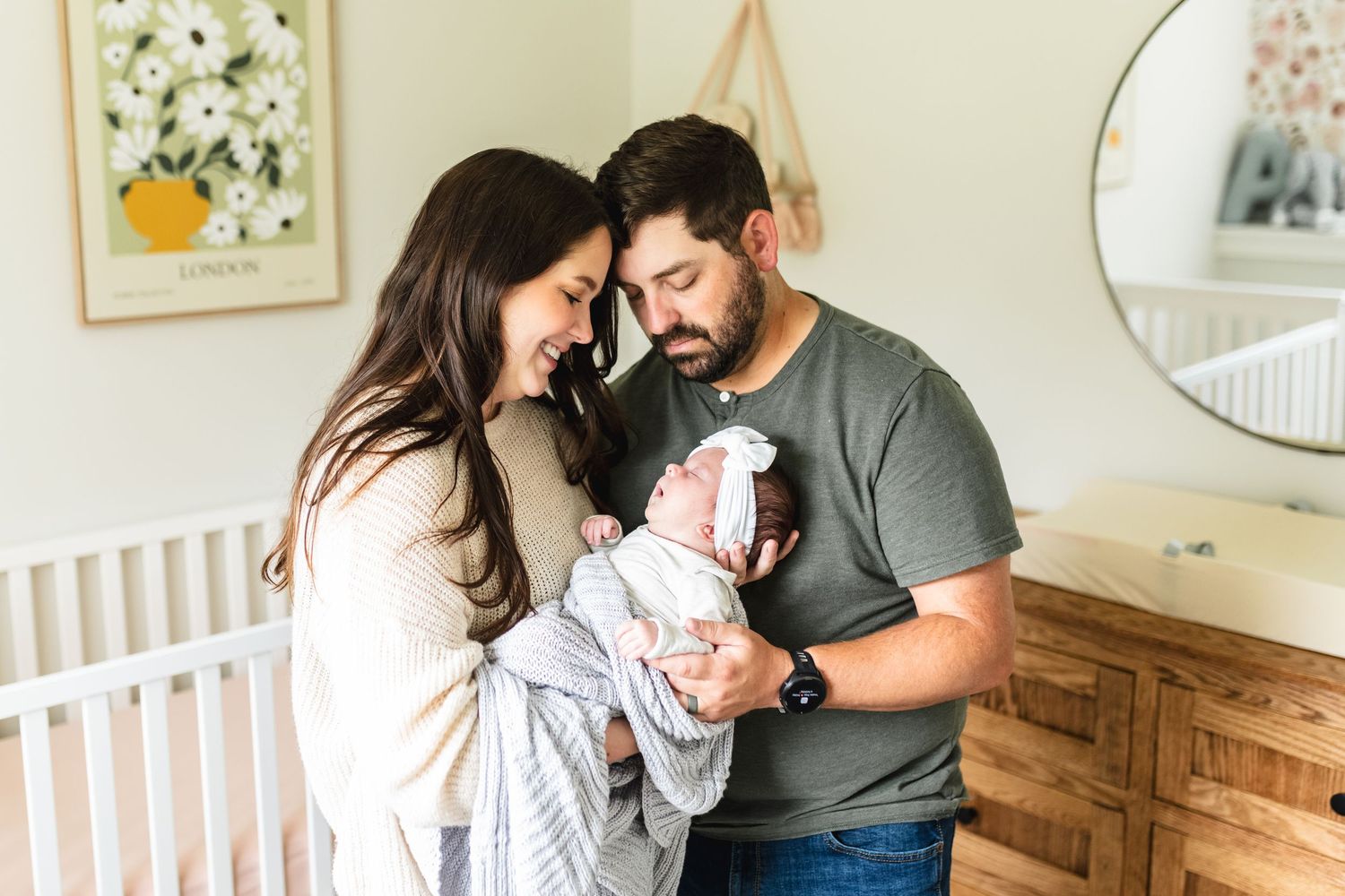 New parents holding their newborn girl while she yawns in her nursery.