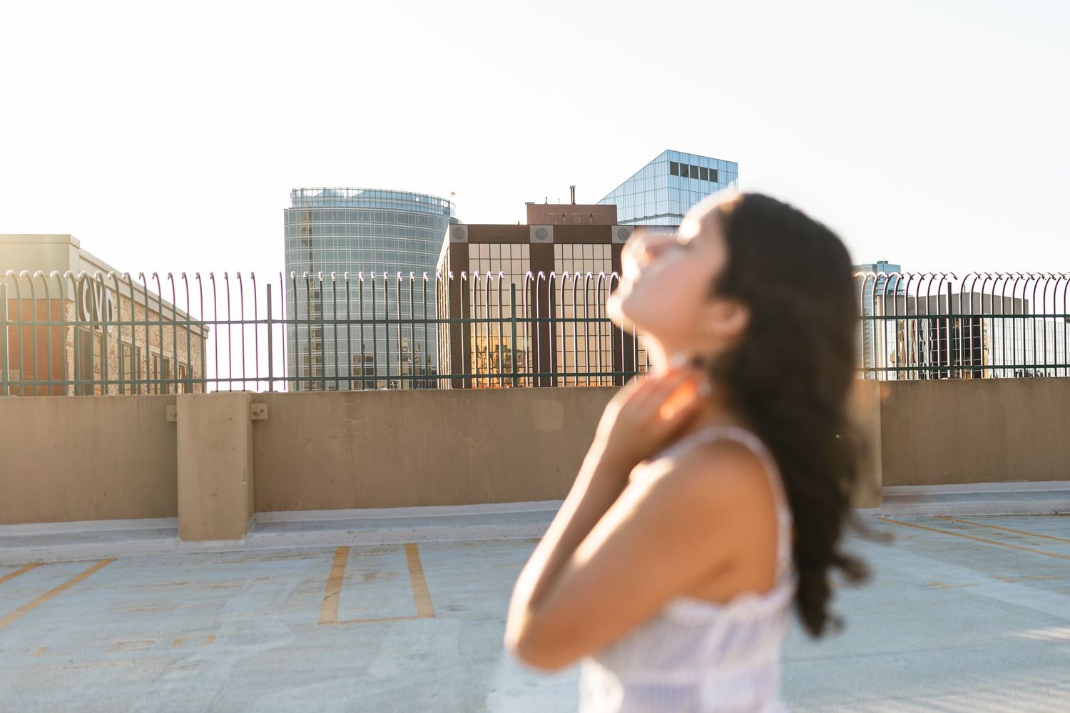 An artistic senior portrait of a on out of focus senior girl absorbing the moment, with the Grand Rapids skyline in the background.
