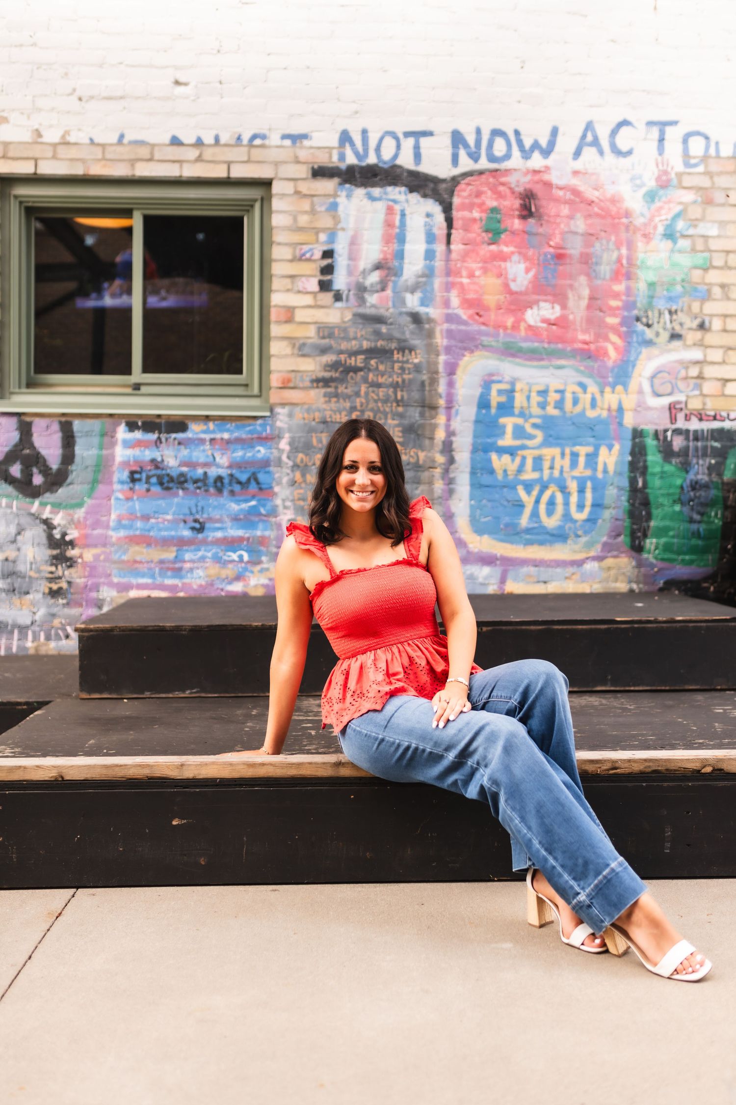 A senior girl posing for a portrait in front of a mural in Muskegon, MI.