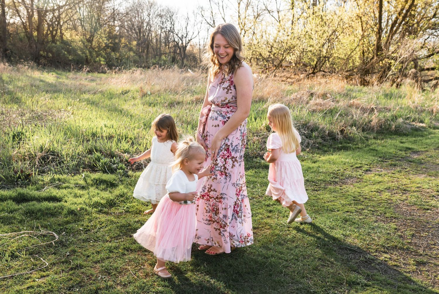 Portrait of a mother laughing as her 3 young girls run around her.