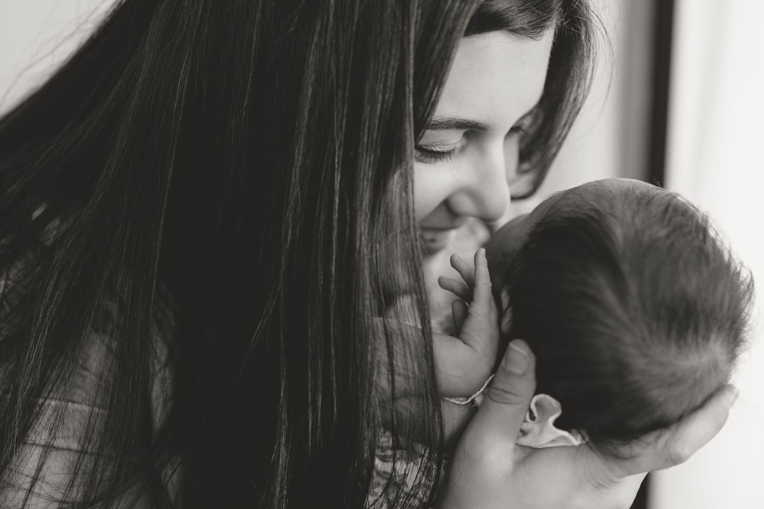 A mother lovingly holds and nurtures her baby in a series of tender black and white photographs.