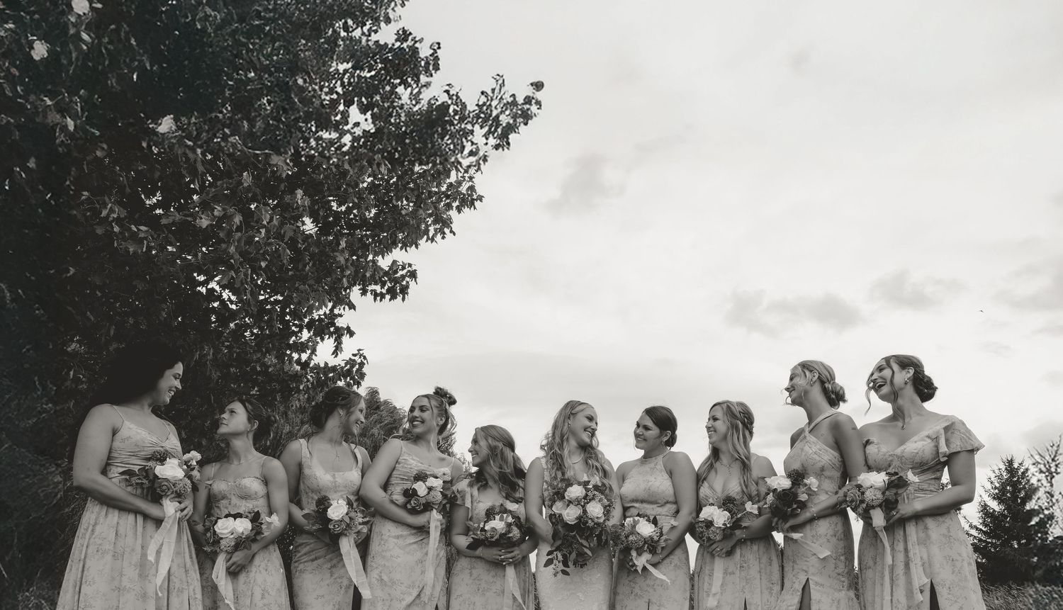 A series of black and white wedding party photos arranged in a panoramic style showing an outdoor celebration.