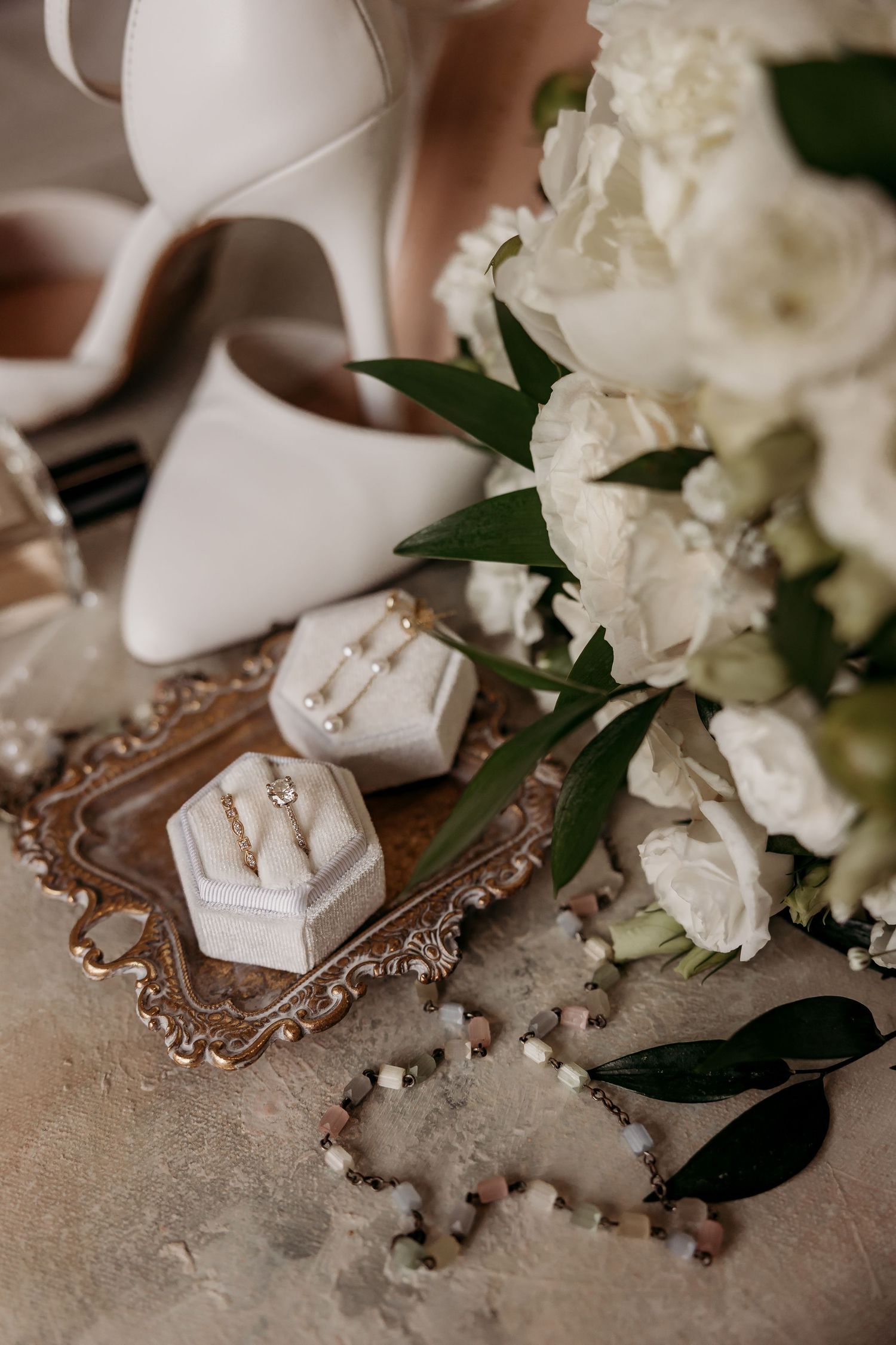 Close-up view of wedding rings displayed in an ornate white box with floral accents and decorative details.