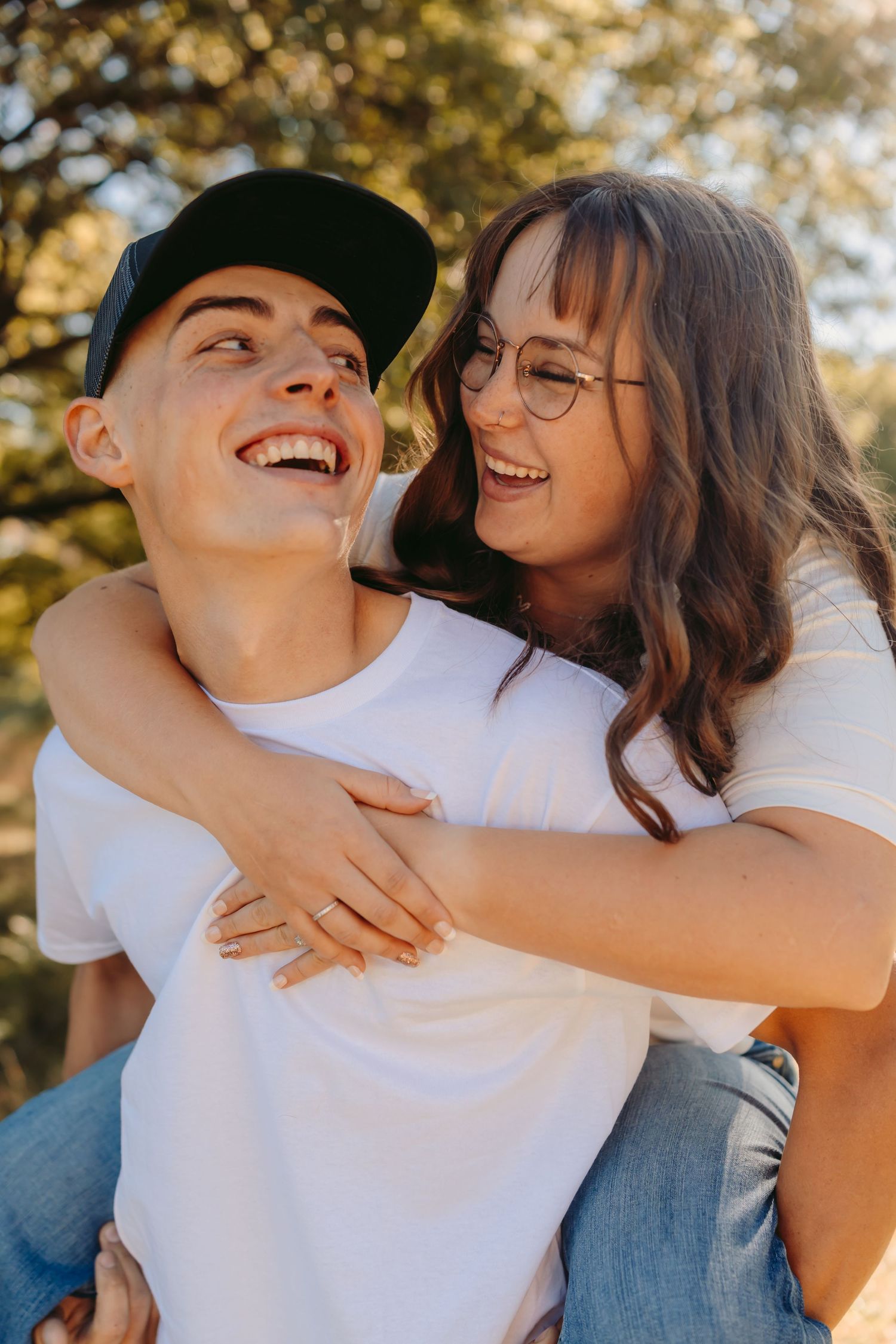 A joyful couple laughing and embracing outdoors on a sunny day, showing genuine happiness and connection.