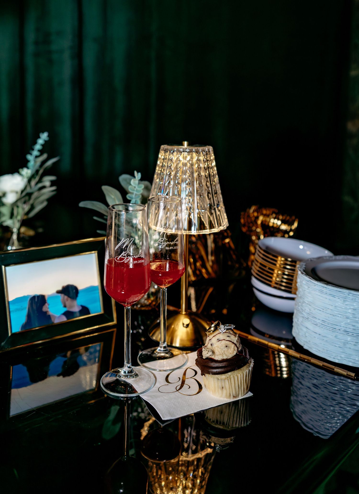 Elegant wedding reception table with red champagne flutes, crystal lamp, and monogrammed card.