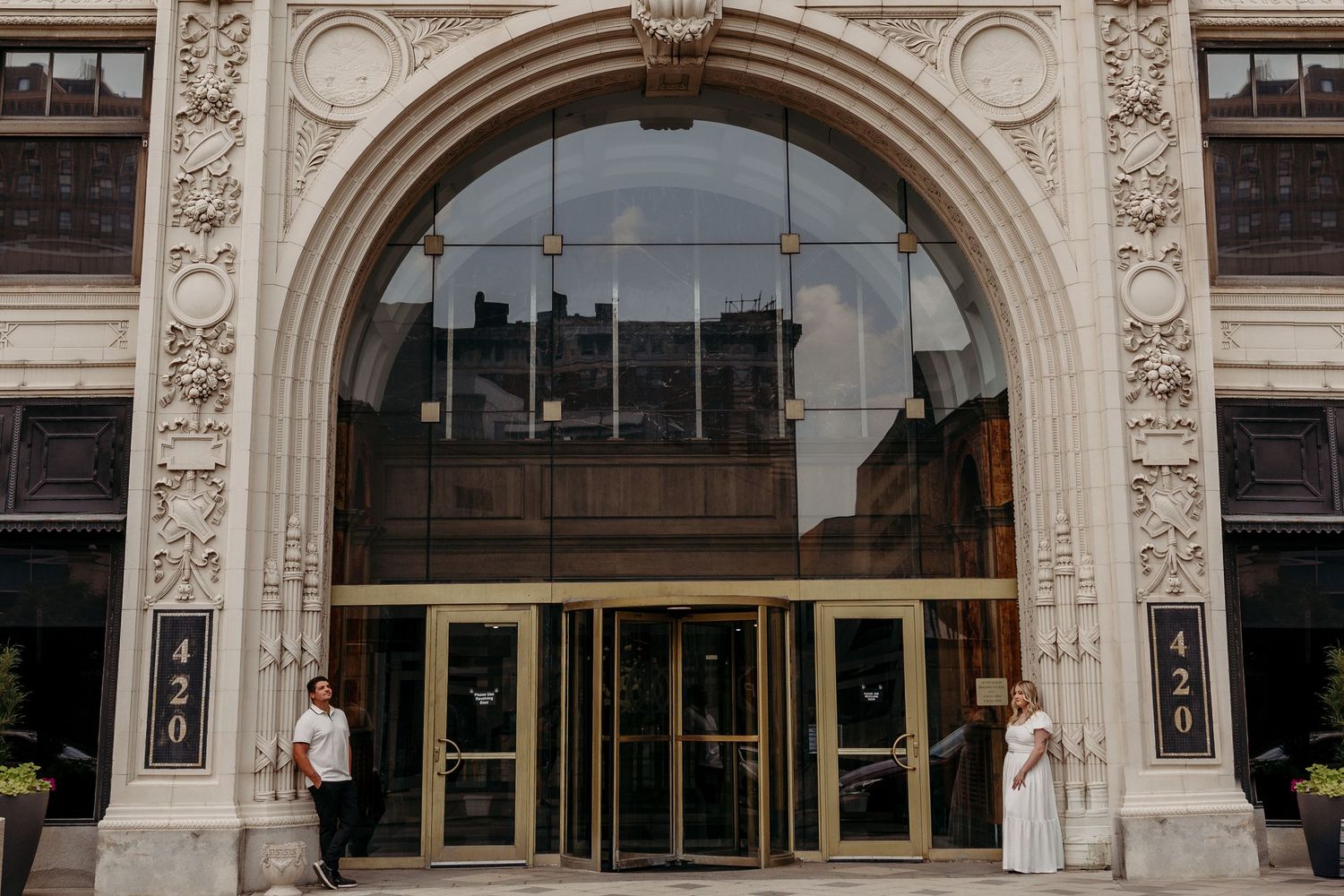 Ornate white stone archway entrance to a historic building with decorative architectural details and glass doors.