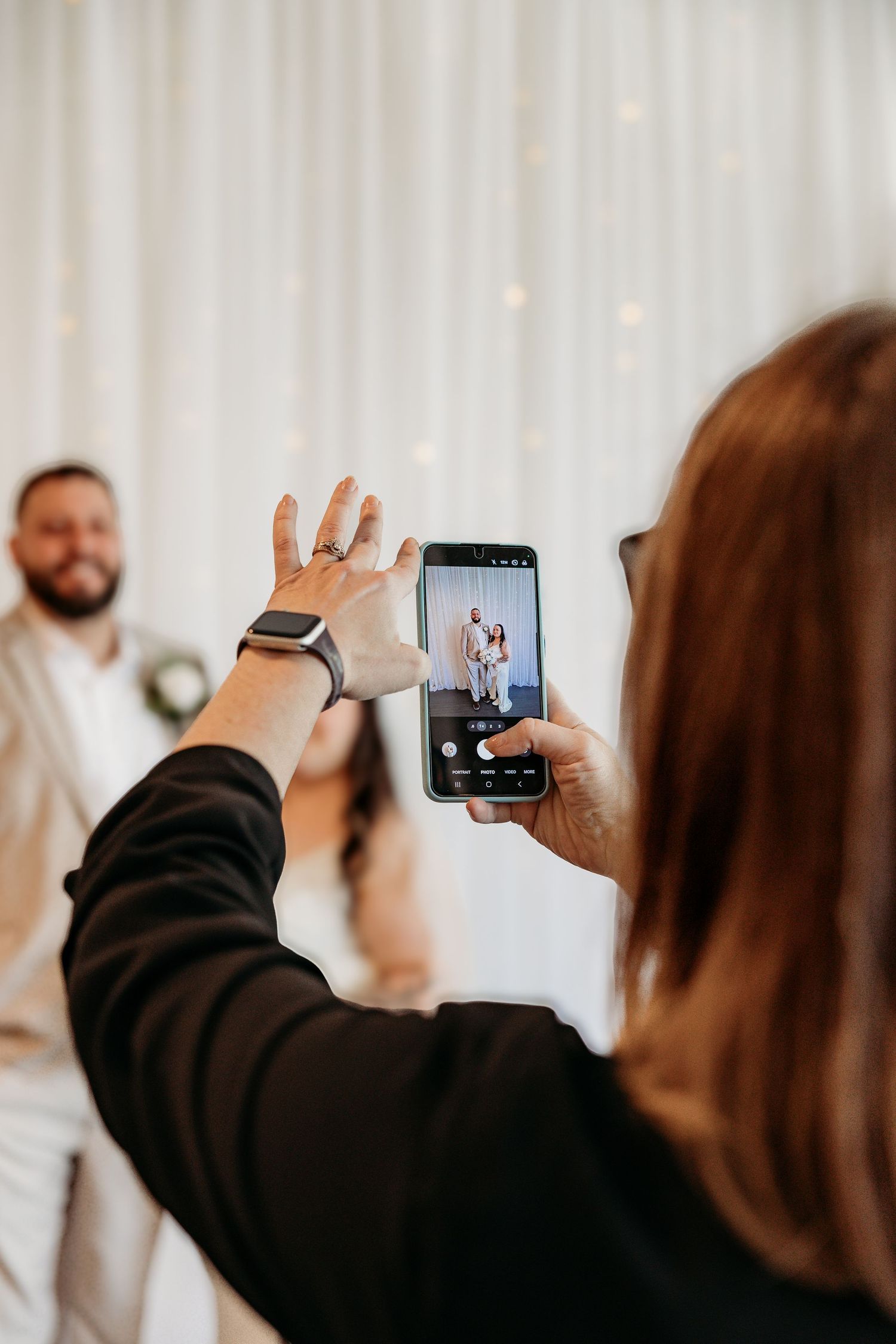 Wedding guests recording videos on smartphones during celebration at reception venue.