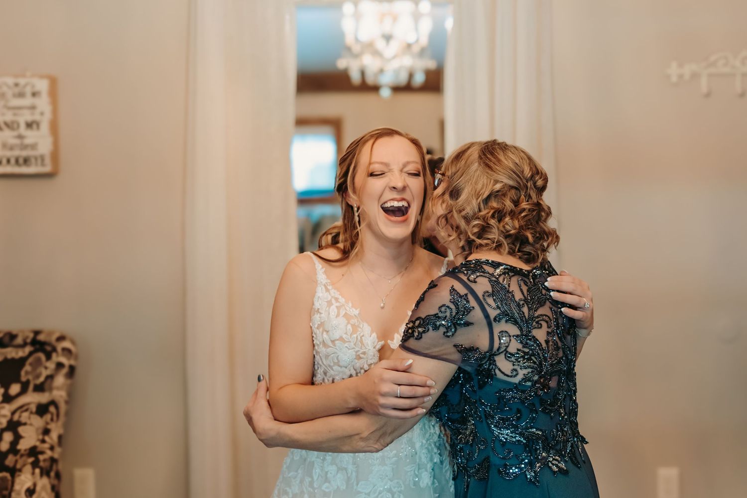 Two people in elegant blue dresses share an emotional embrace while celebrating a special occasion.