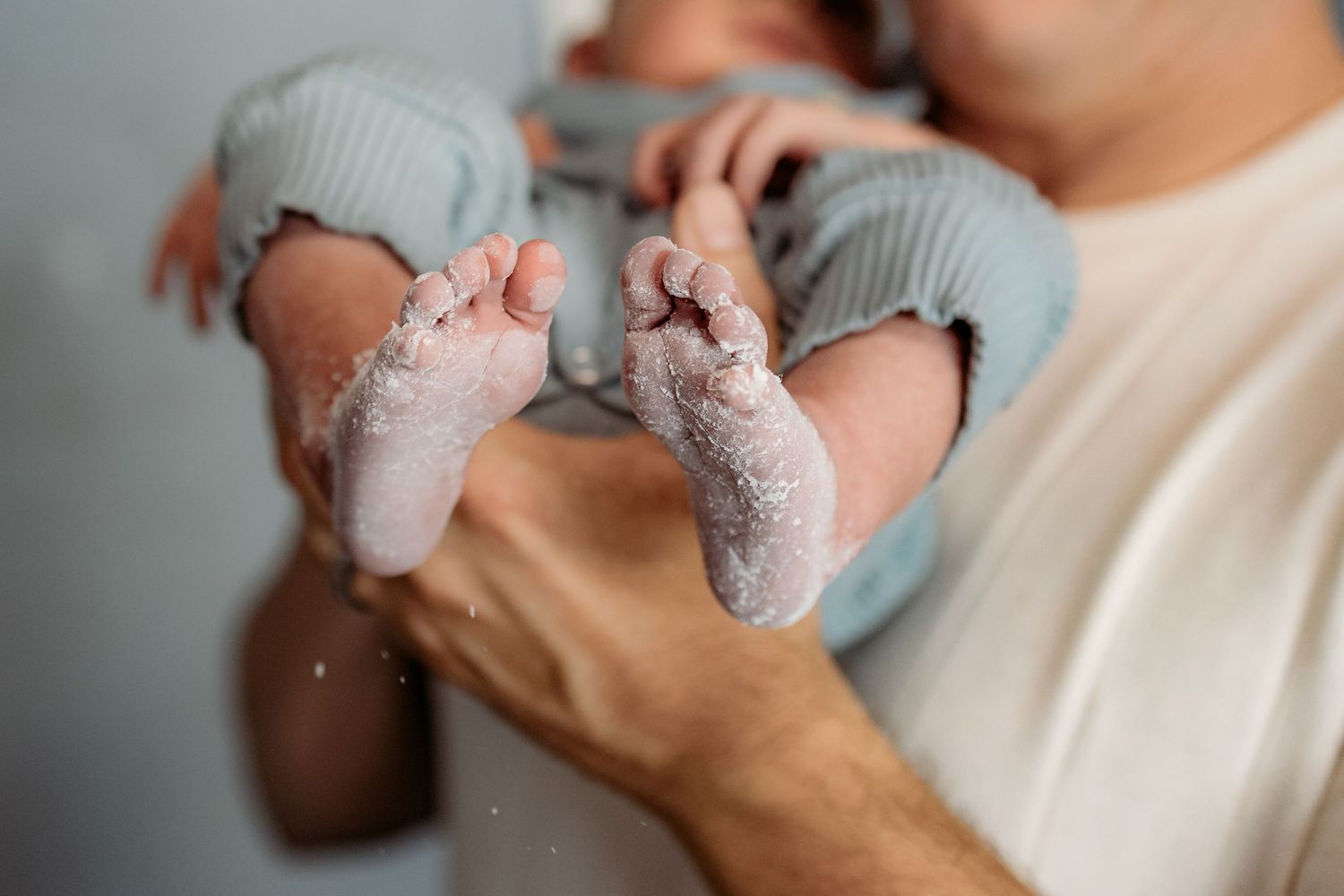 A series of intimate photos showing tender moments between caring hands and a baby in gray clothing.