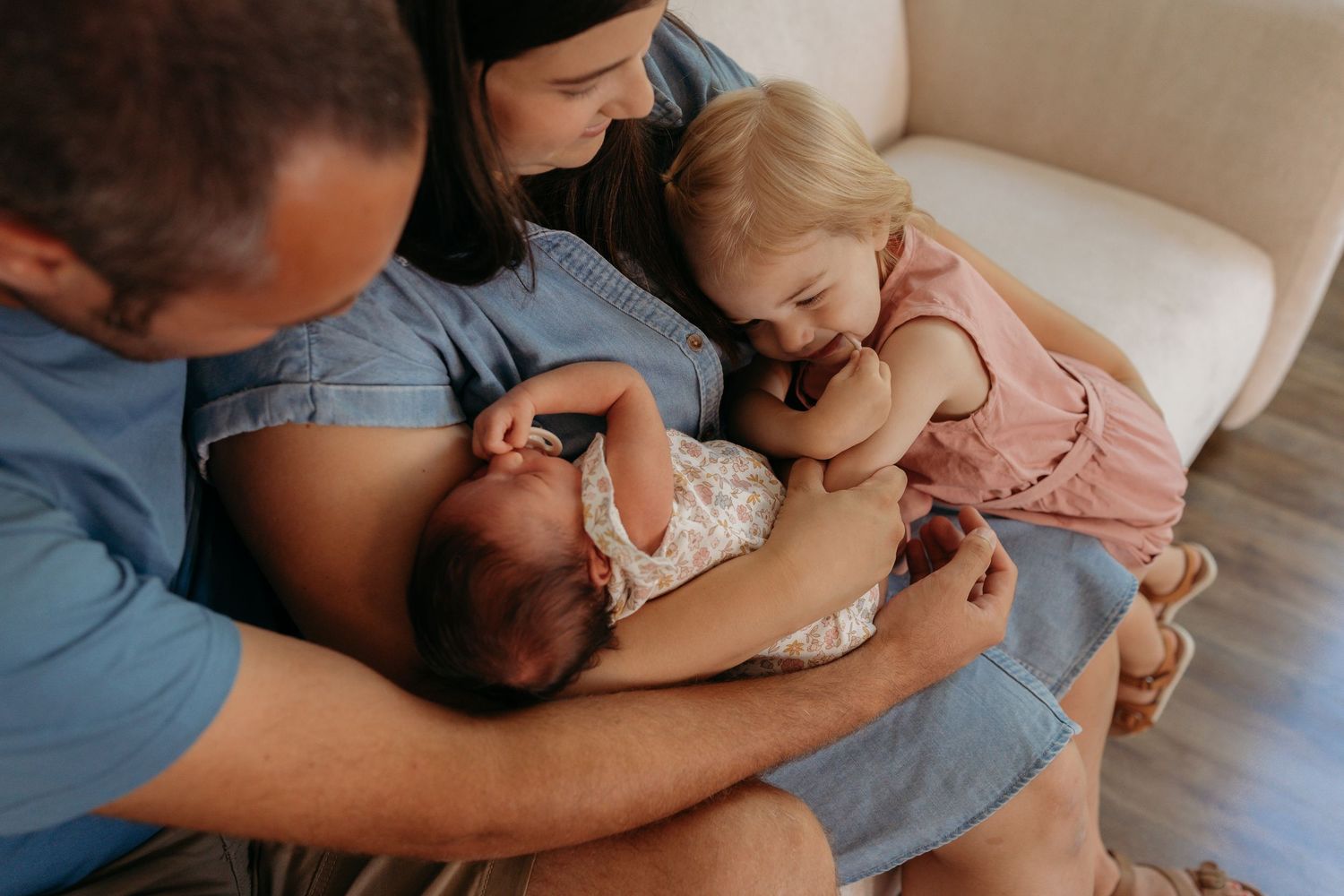 Tender family moment as parents and toddler relax together on a cozy white couch at home.