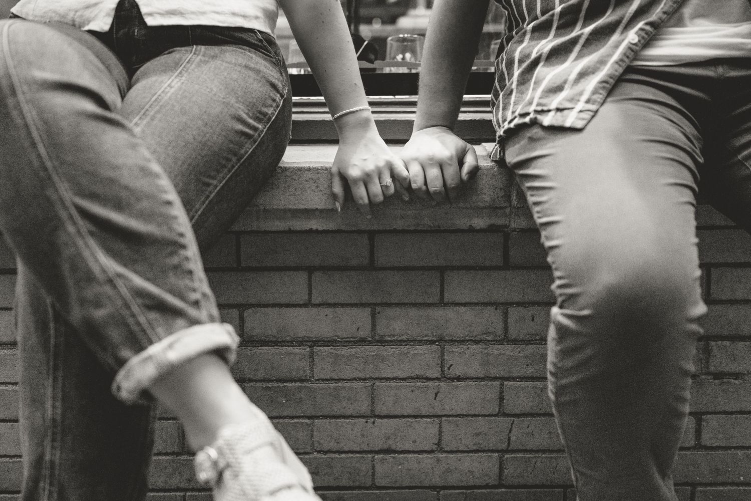 Close-up black and white image of hands folding or rolling up denim jeans.