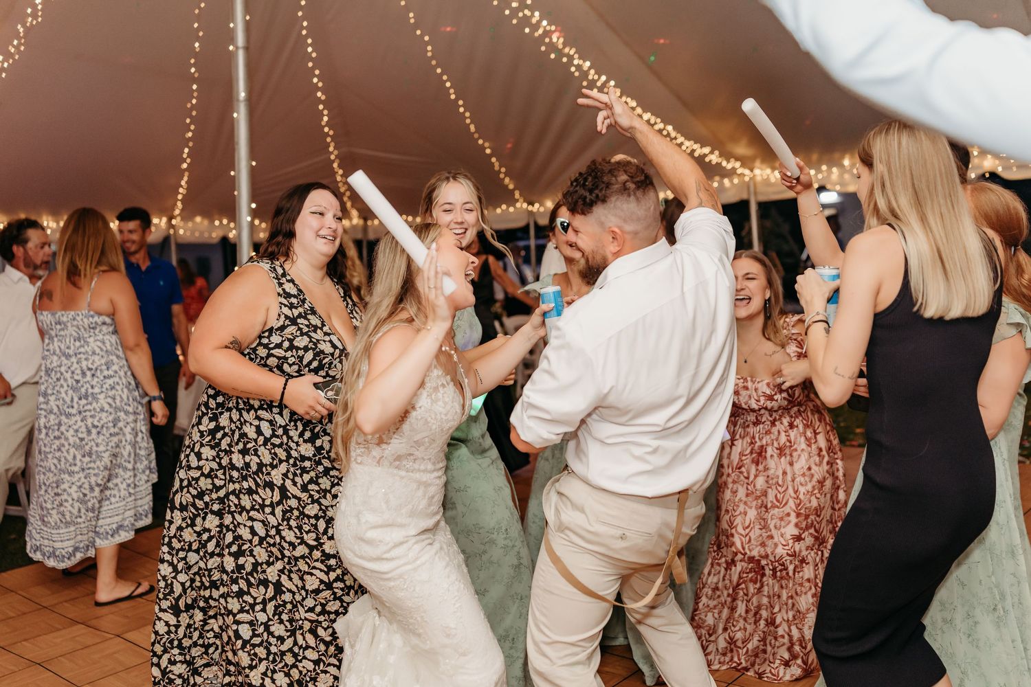 People dance and celebrate together on the dance floor at a wedding reception.