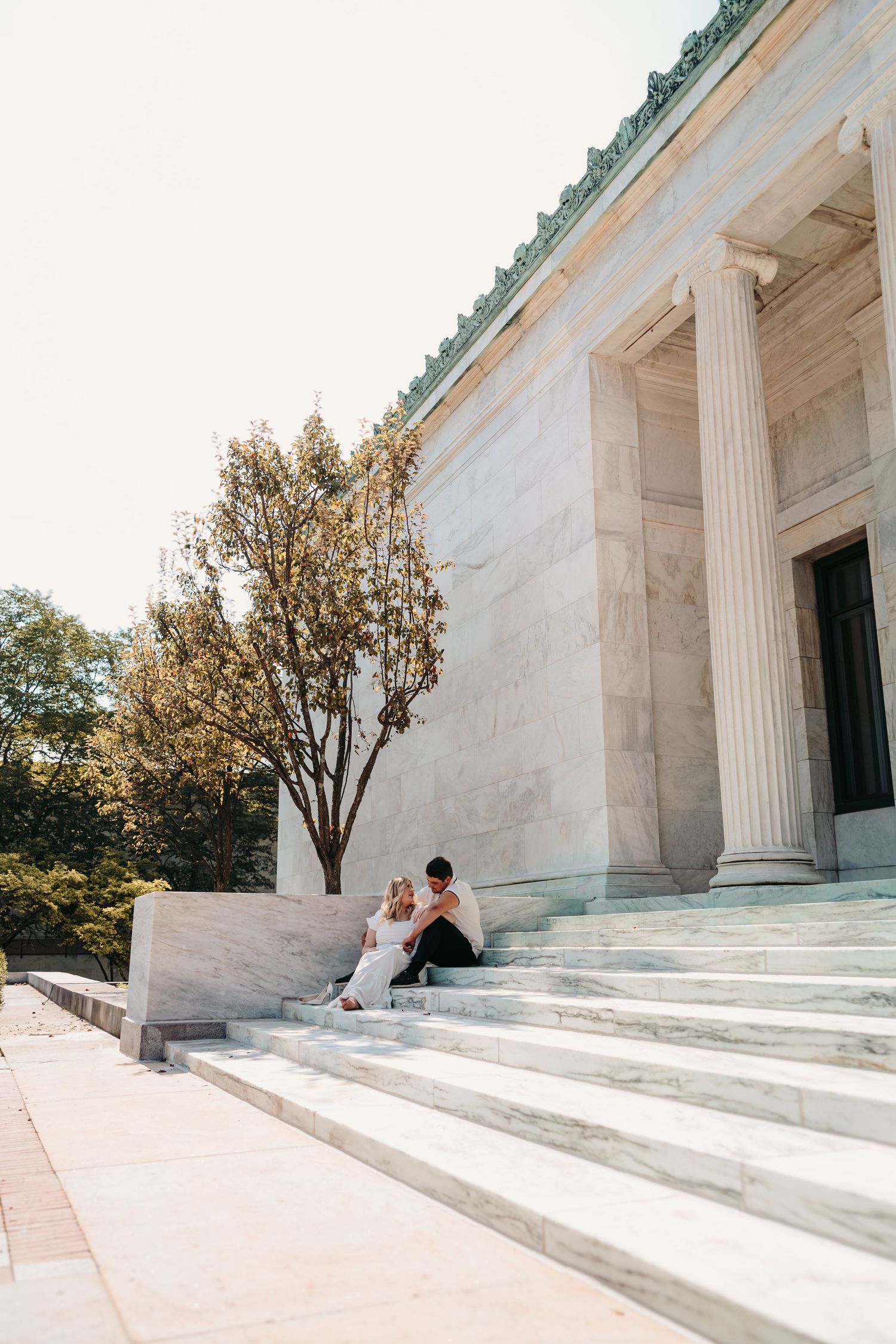 A series of four photos showing a couple sitting on white marble steps of a neoclassical building during a sunset.