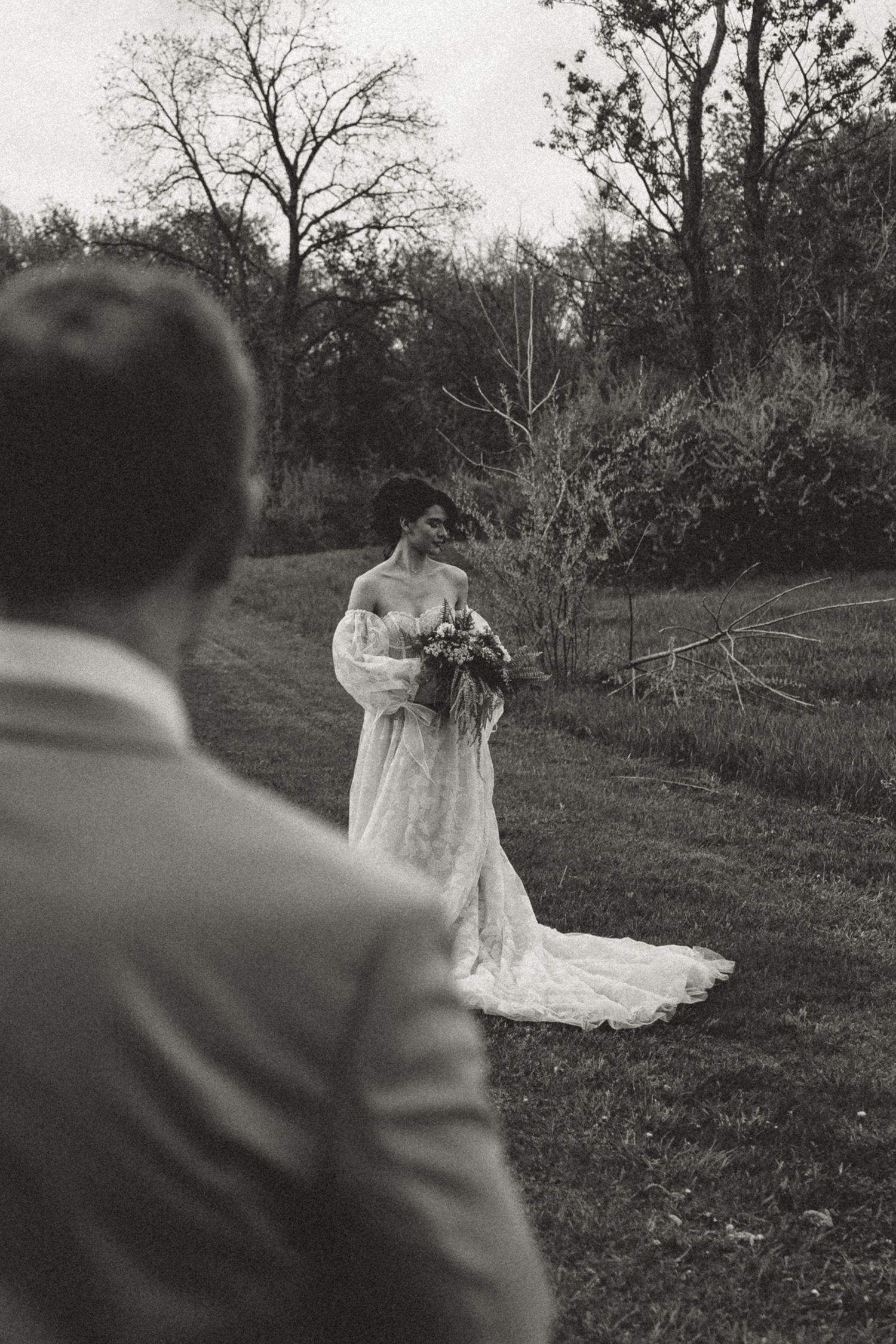 Black and white photo showing a wedding moment captured in an outdoor garden setting with trees and grass.