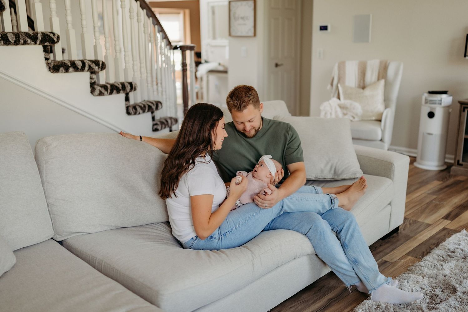 Young family sitting together on a gray couch in their bright modern living room.