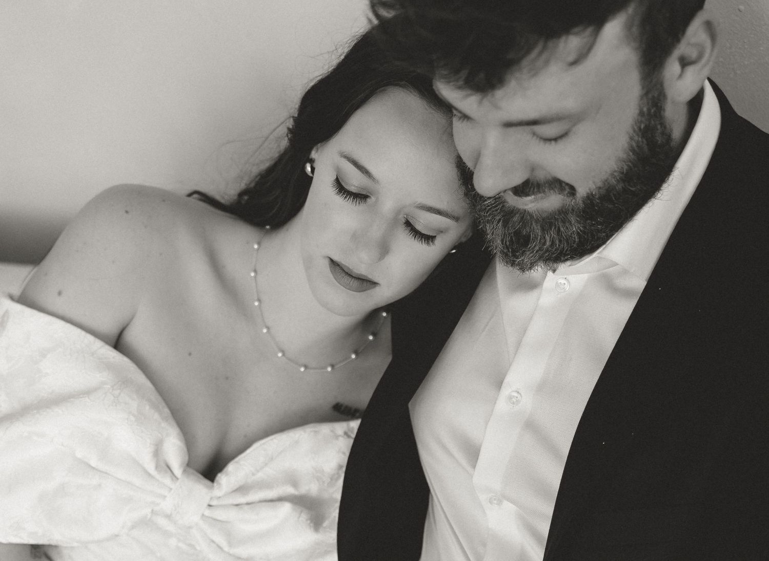 Black and white romantic wedding photos showing tender moments between newlyweds in elegant formal attire.