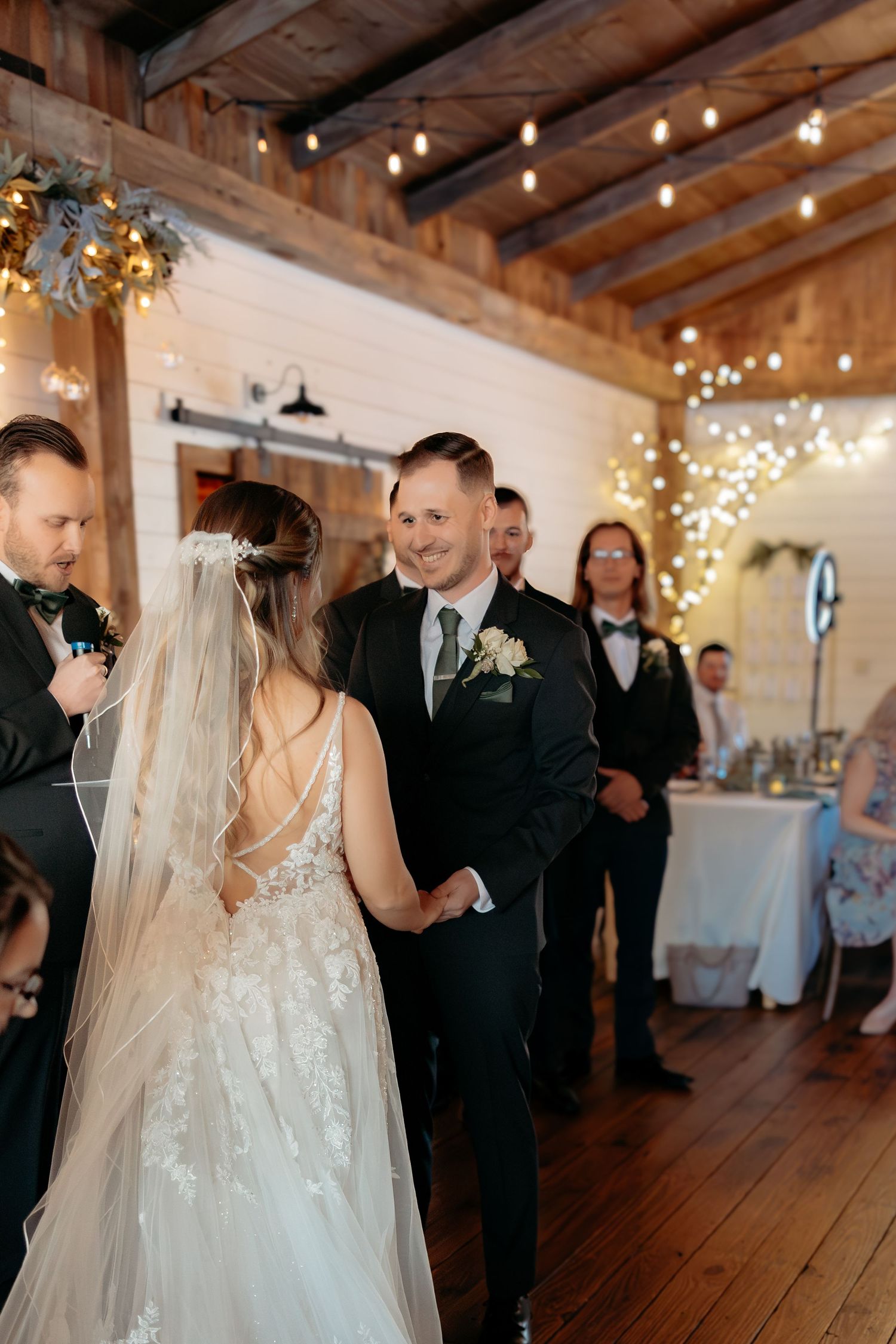 A touching first look moment between bride and groom in a rustic barn venue decorated with twinkle lights.