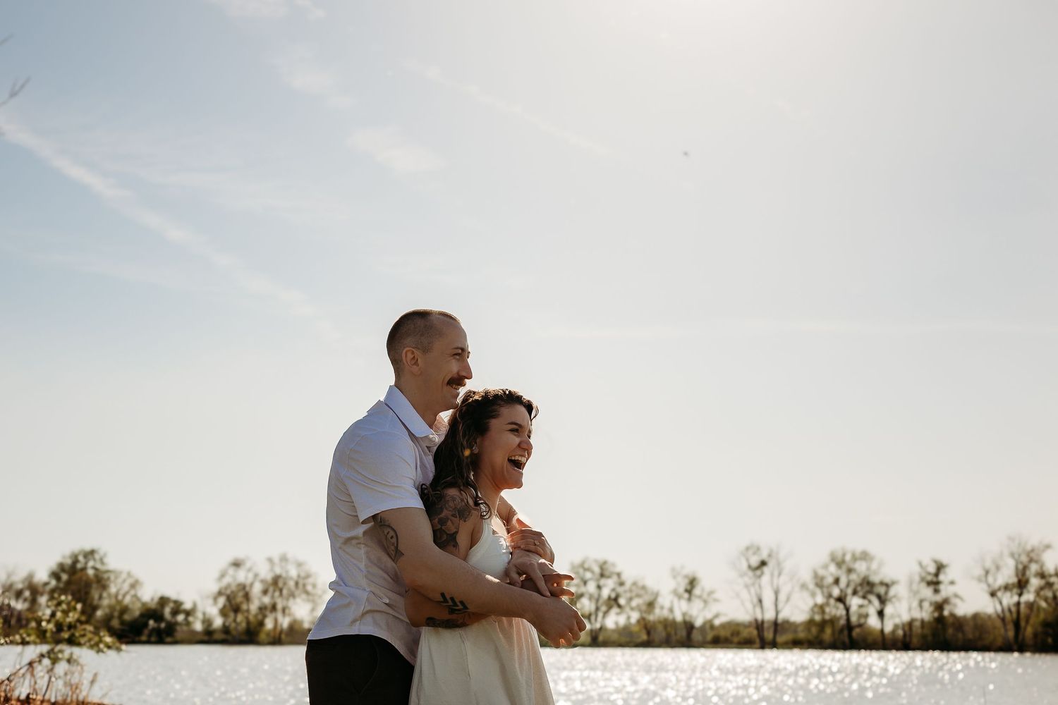 A couple embraces in a tender moment during a sunset photoshoot in a natural outdoor setting.