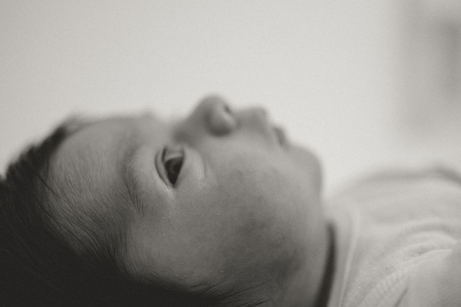 A person sleeping peacefully on their side with half their face visible against a light background.