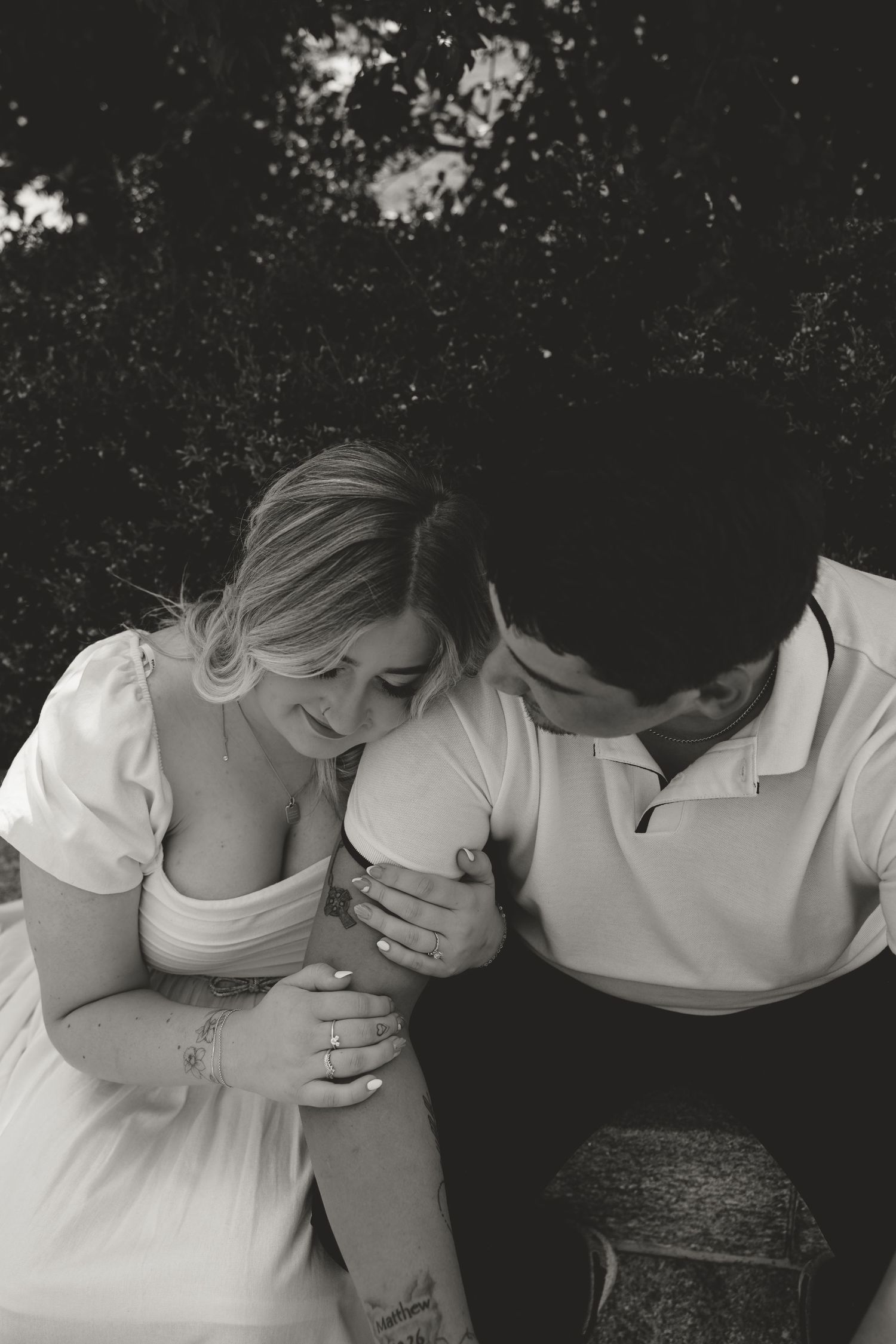 Black and white photo series showing a couple in white clothing embracing intimately against a dark background.