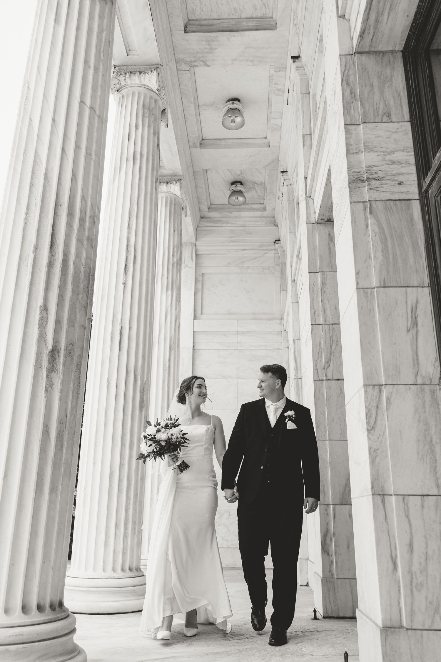 Several black and white wedding photos showing a couple walking through elegant classical stone columns.