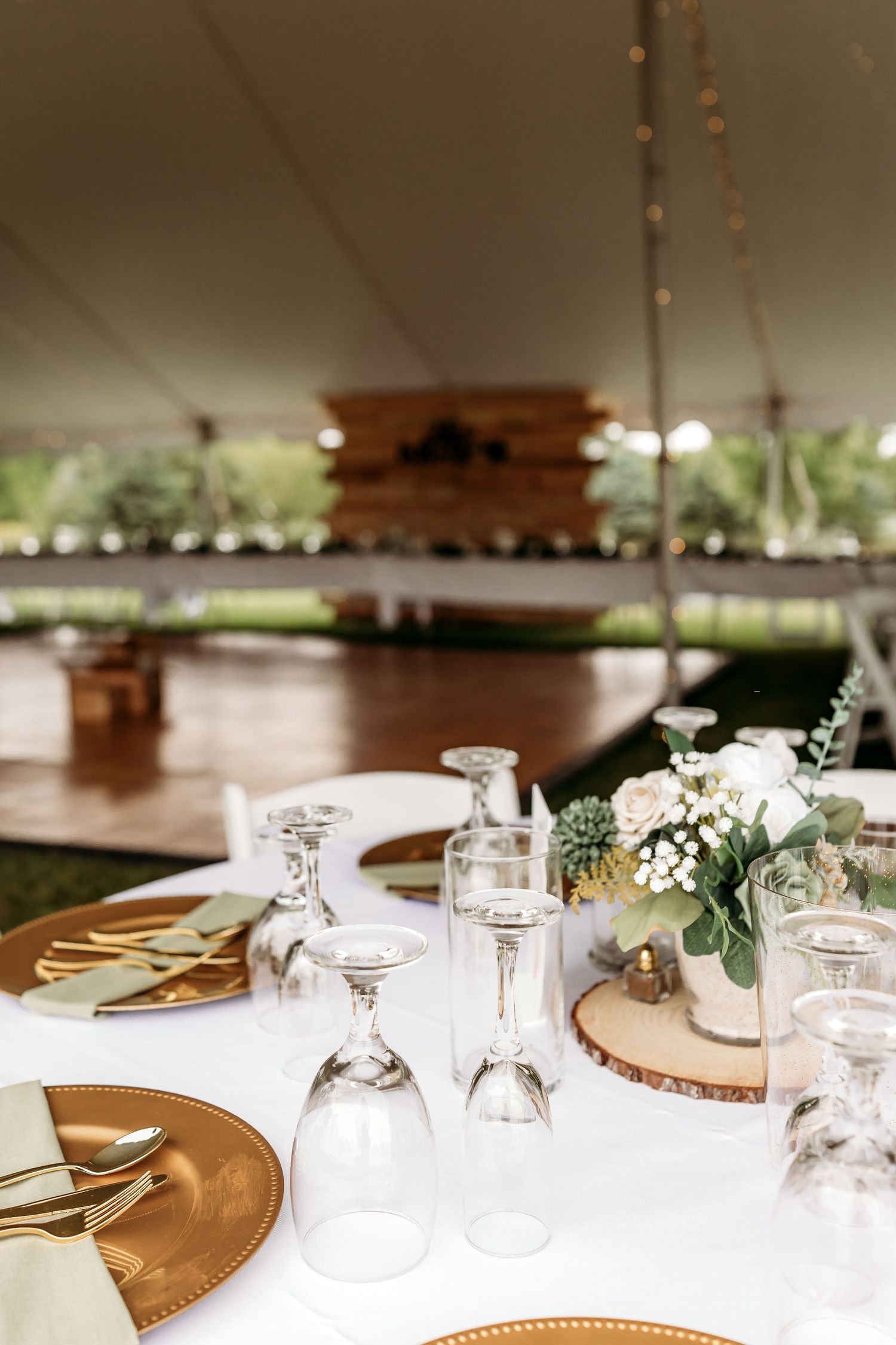 Elegant wedding reception table setting with gold charger plates, crystal glassware and delicate floral centerpieces.