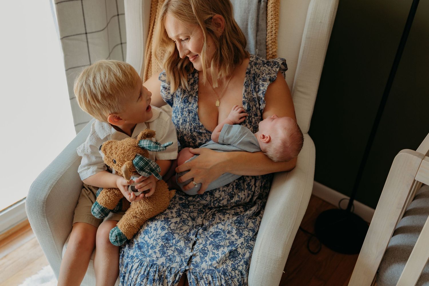 A candid family moment captured in soft lighting on a couch with a blue floral dress and khaki shorts.