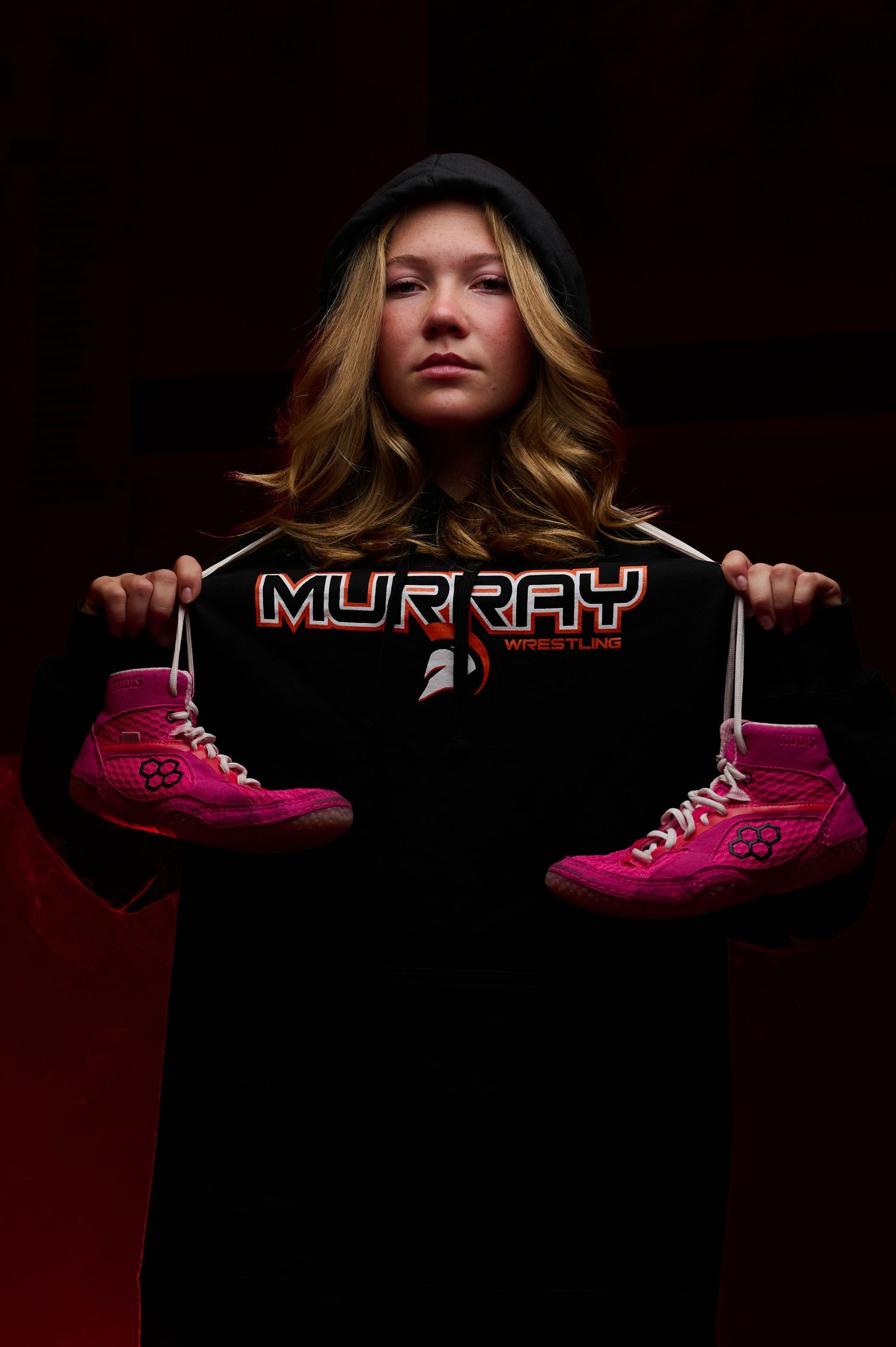 Sport Portrait of blonde girl wrestler wearing Murray High hoodie holding wrestling shoes
