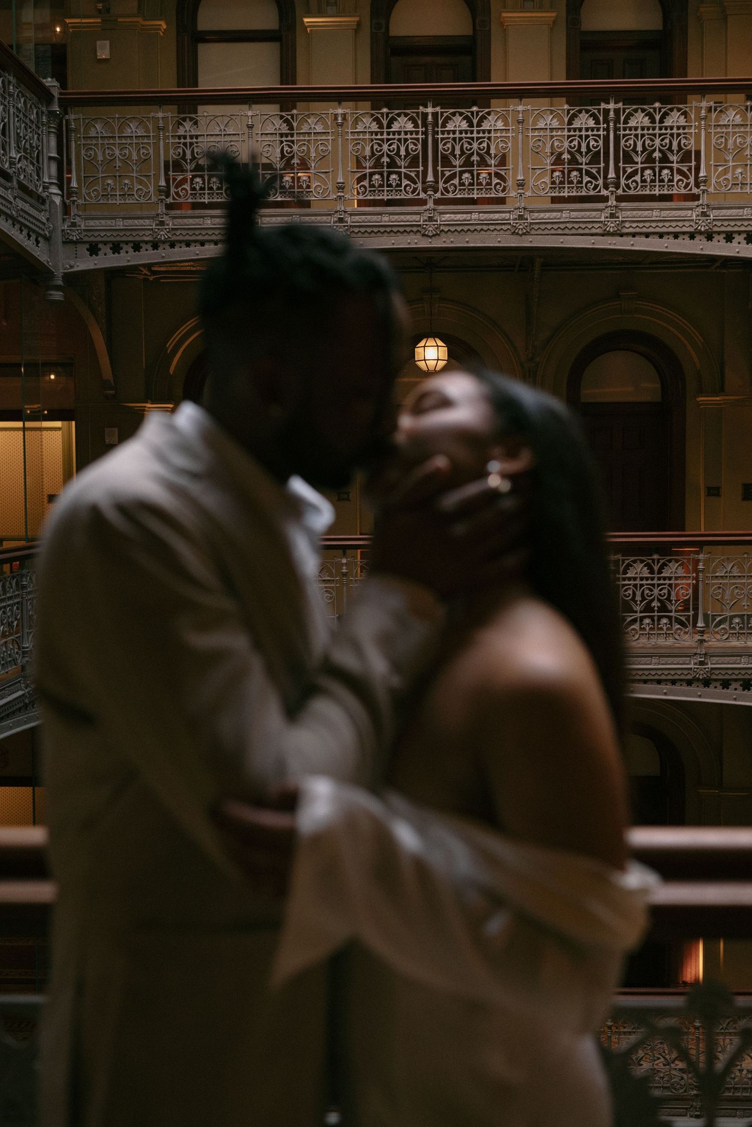 Couples dancing in an ornate ballroom with vintage architectural details and dim lighting.