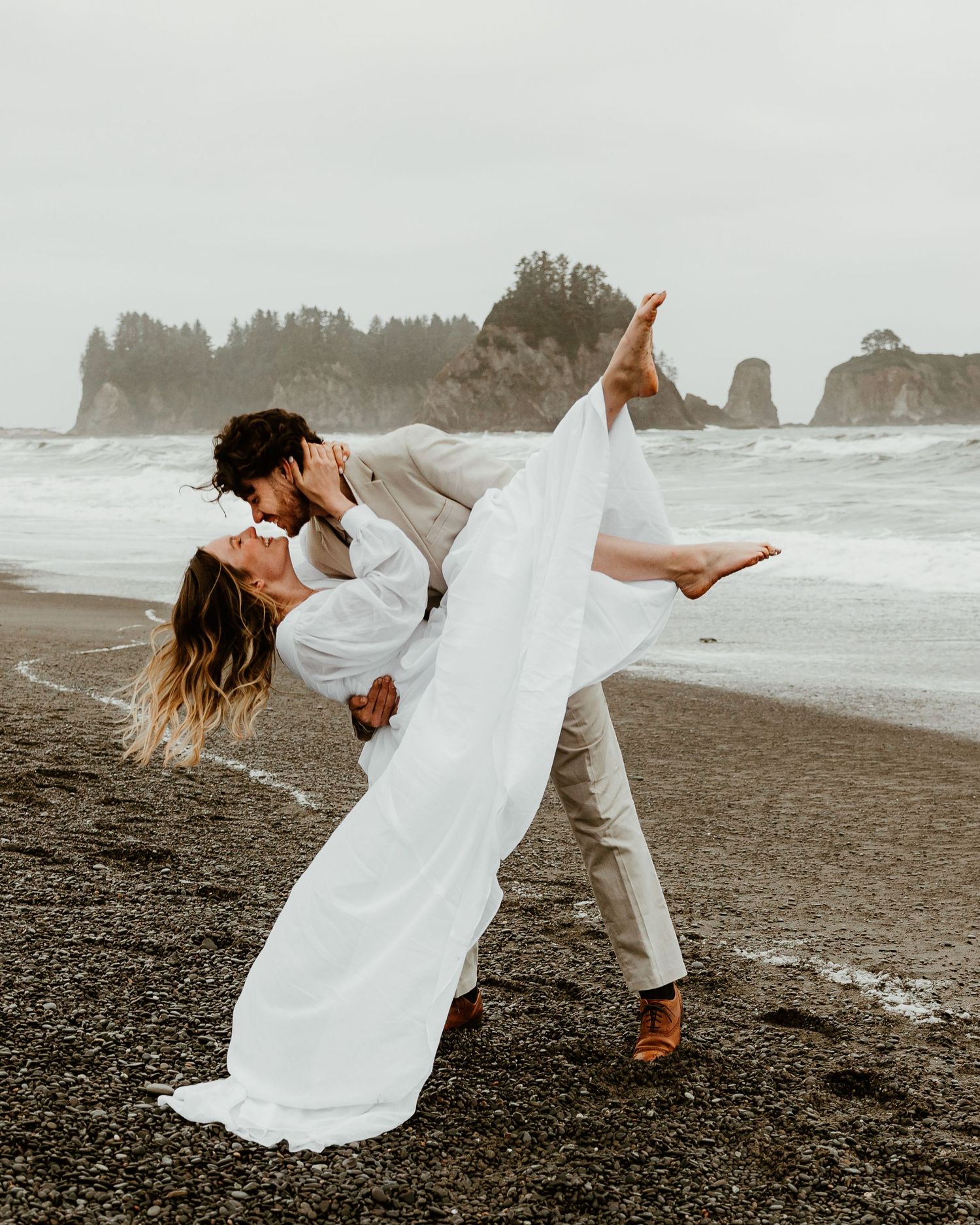 Dramatic wedding portraits on a moody black sand beach with sea stacks in the background.