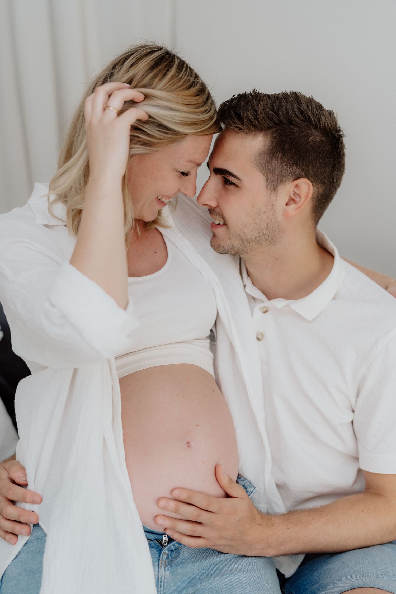 Zärtlicher Moment zwischen werdenden Eltern beim Homestory-Babybauchshooting