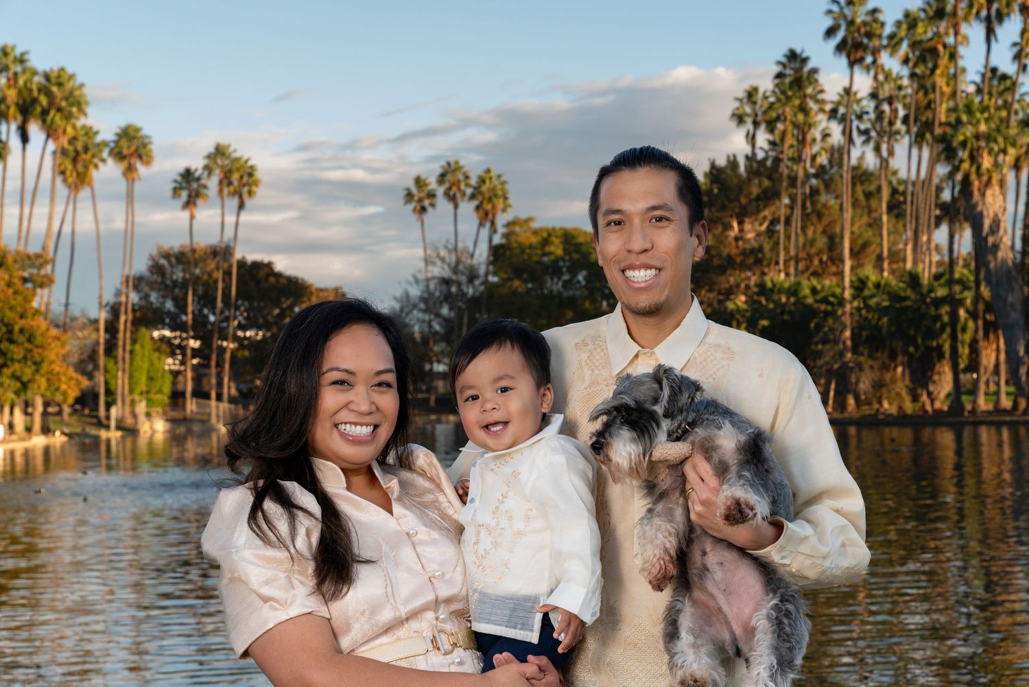 Family portrait session at sunset with palm trees and water in the background.