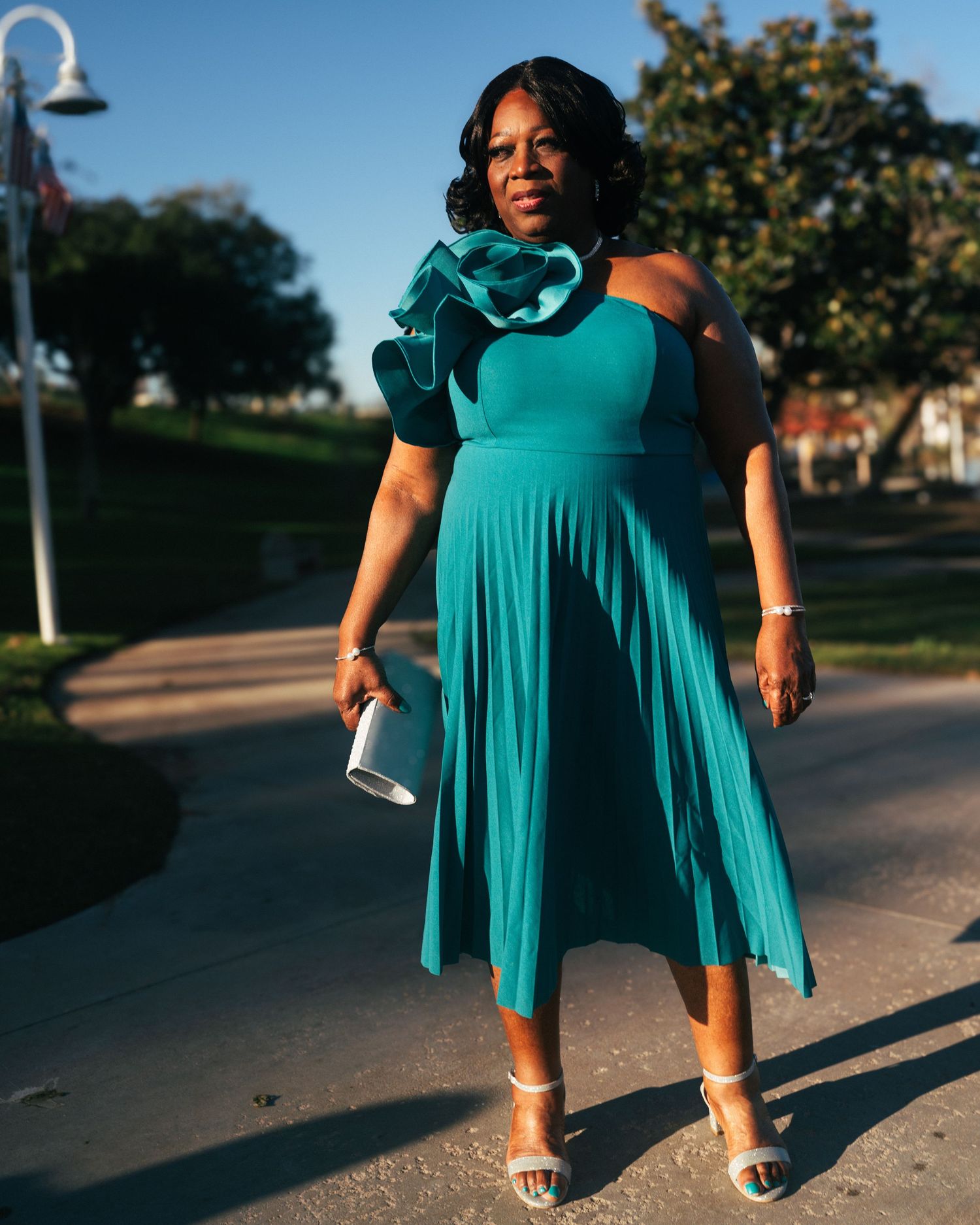 Woman in teal dress walking along a path during a sunset photoshoot.