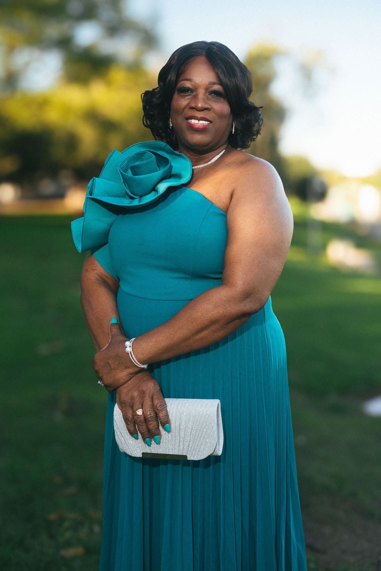 Woman in teal dress smiling during an outdoor portrait session.