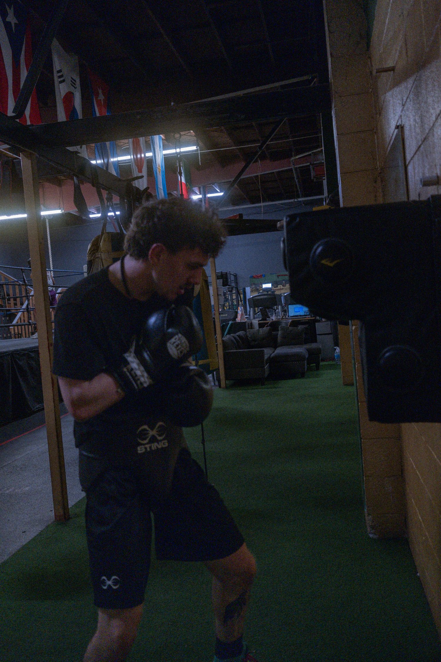 Athletes training in a dark gym space with green turf flooring.