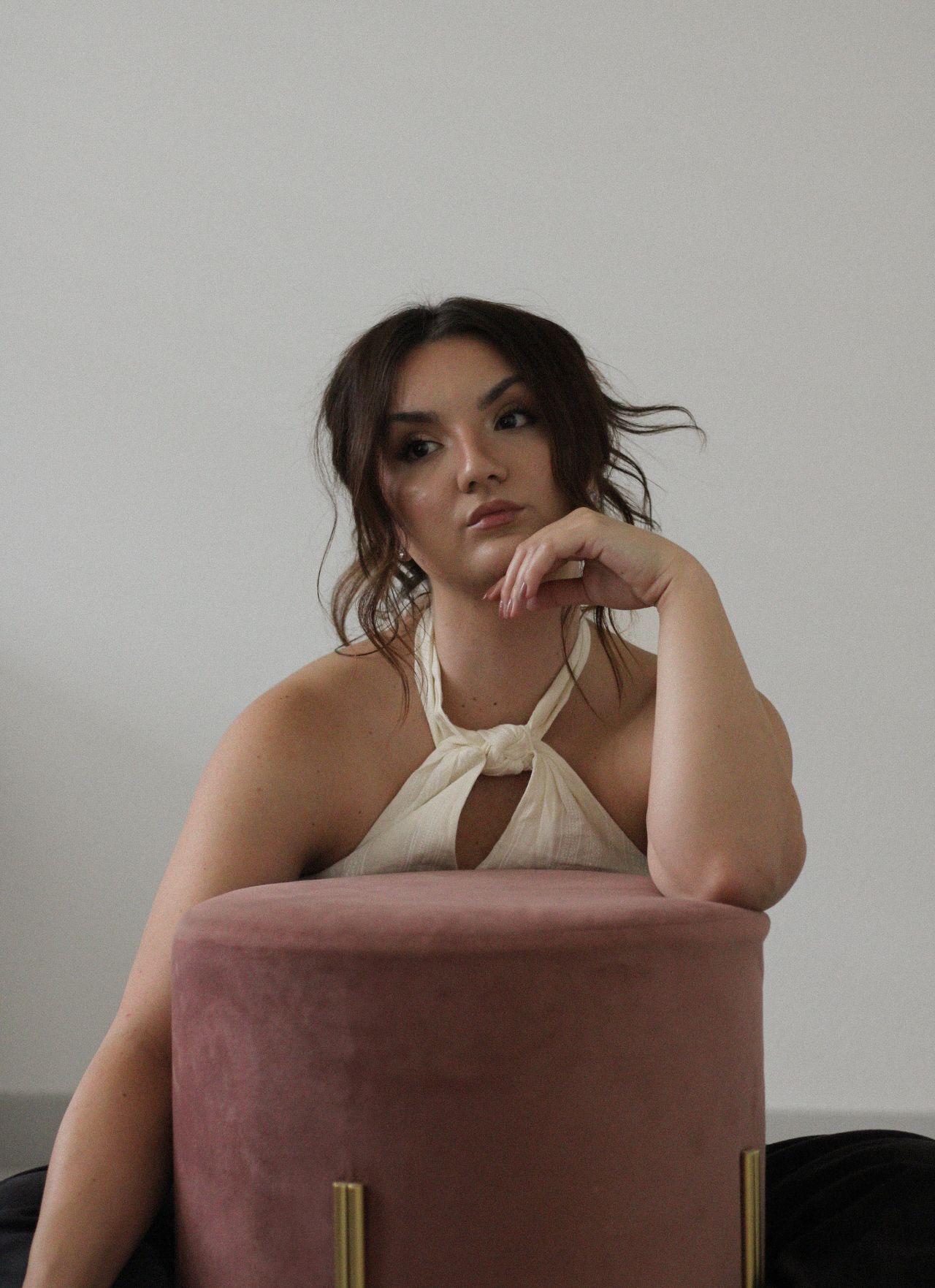 Artistic portrait shot with someone leaning on a dusty rose velvet ottoman.