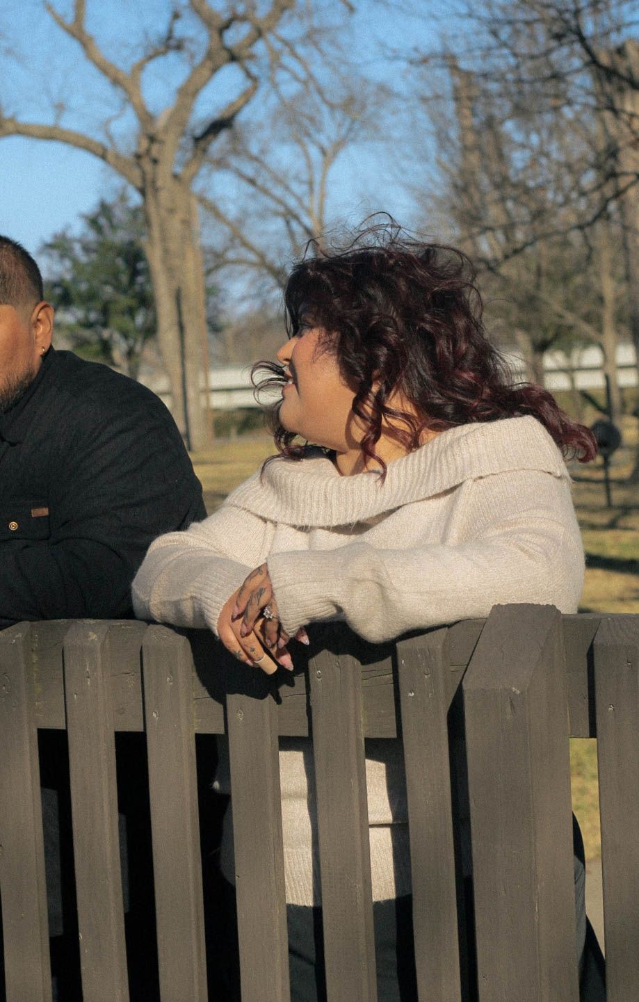Two people leaning on a wooden fence together in a relaxed pose.