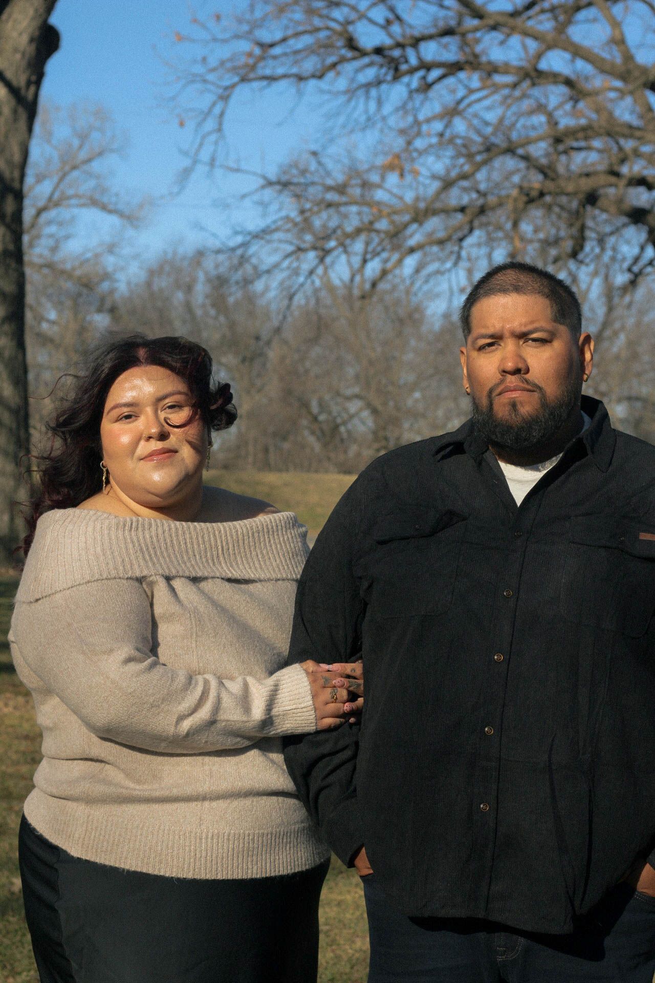 Two people in contrasting outfits embrace in a natural outdoor setting.