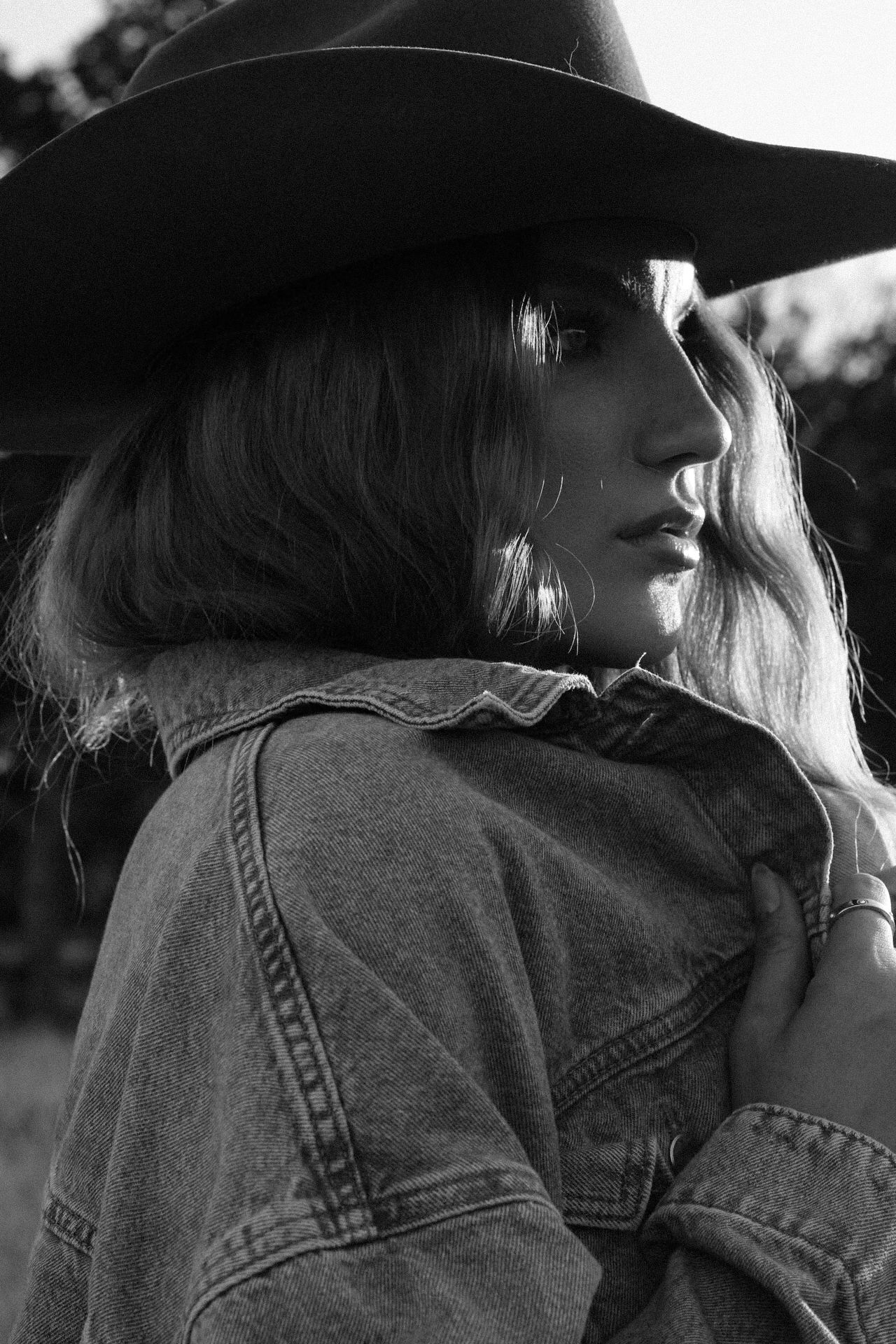 Close-up view of someone wearing a denim jacket and hat in black and white.