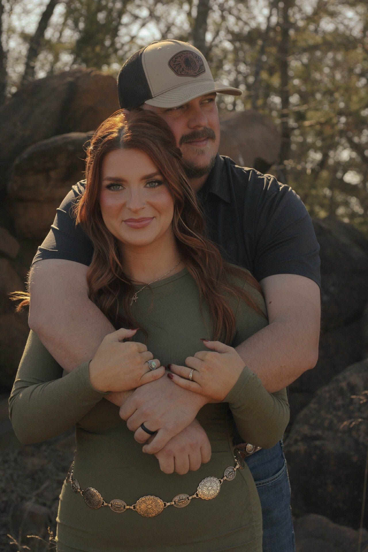 Couple embracing outdoors against natural rocky backdrop.