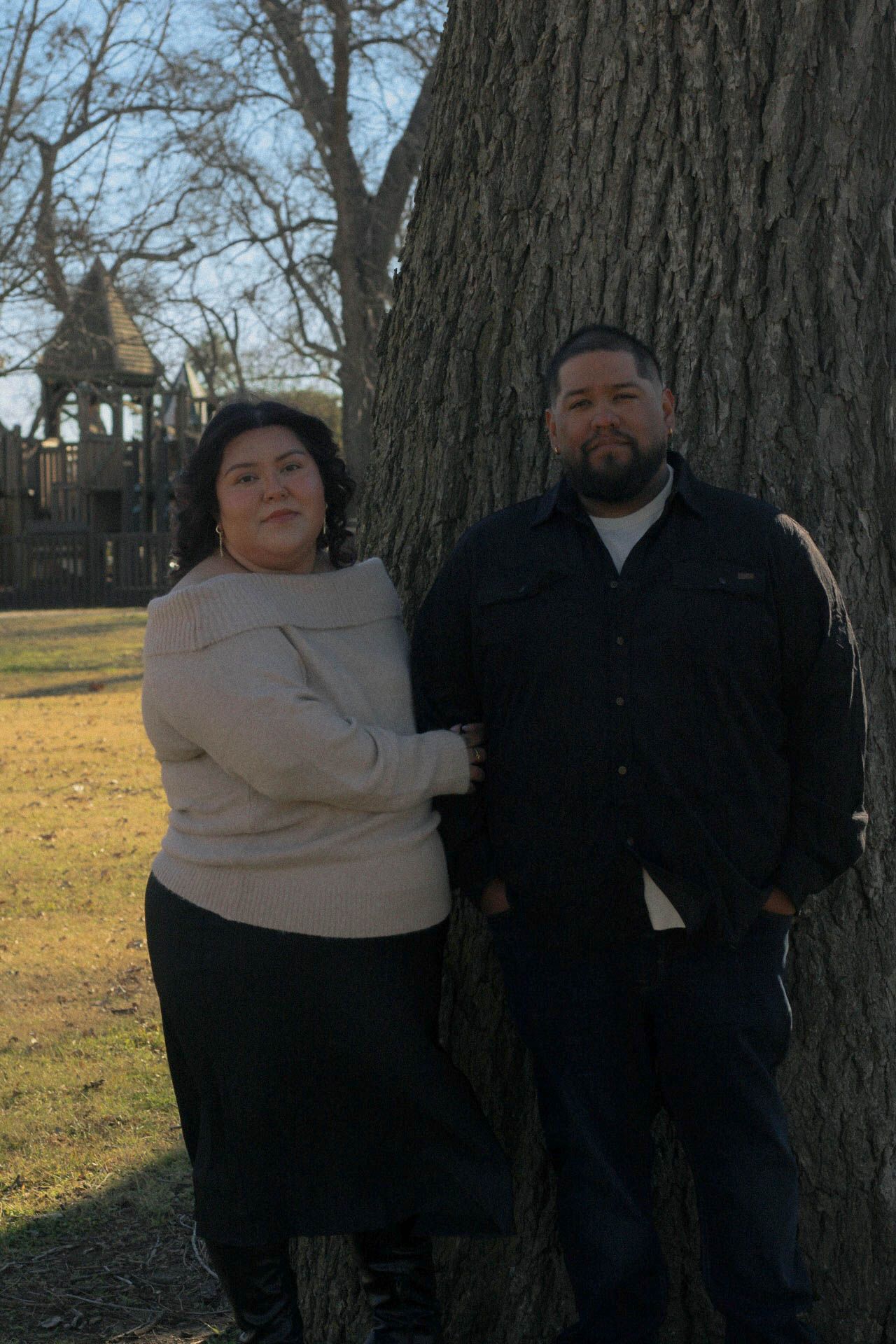 Outdoor portrait session against large tree trunk in park setting.