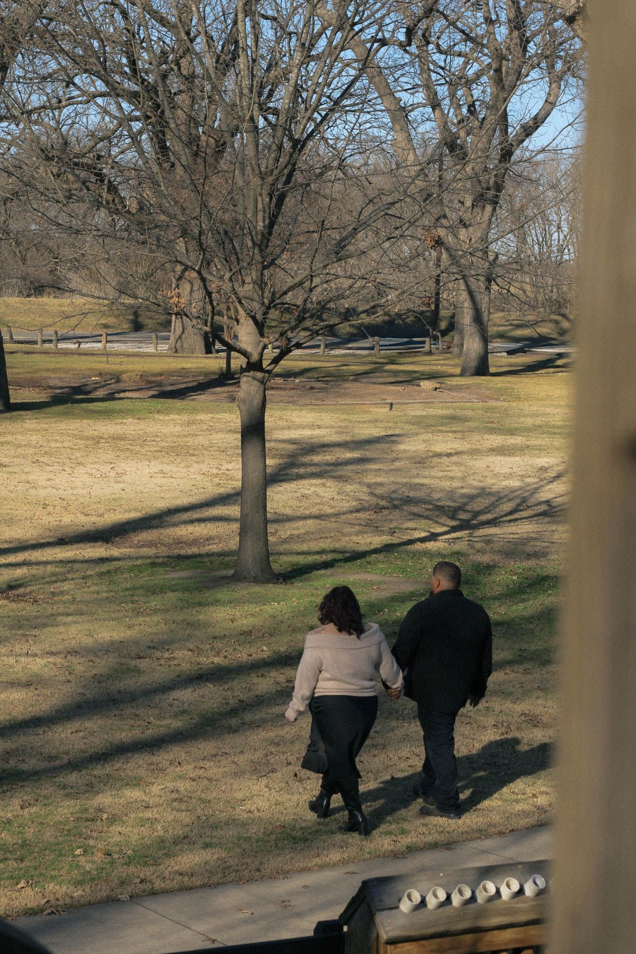 People walking along a winding pathway through a park with dormant winter trees.