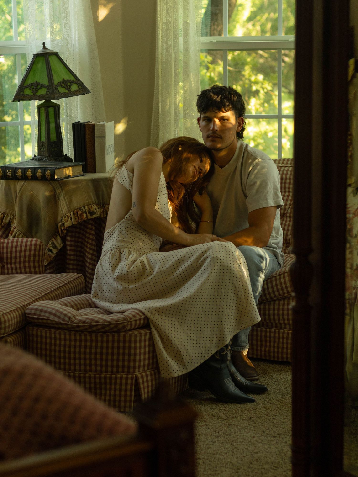 Young couple sitting together on plaid sofa in cozy vintage living room.