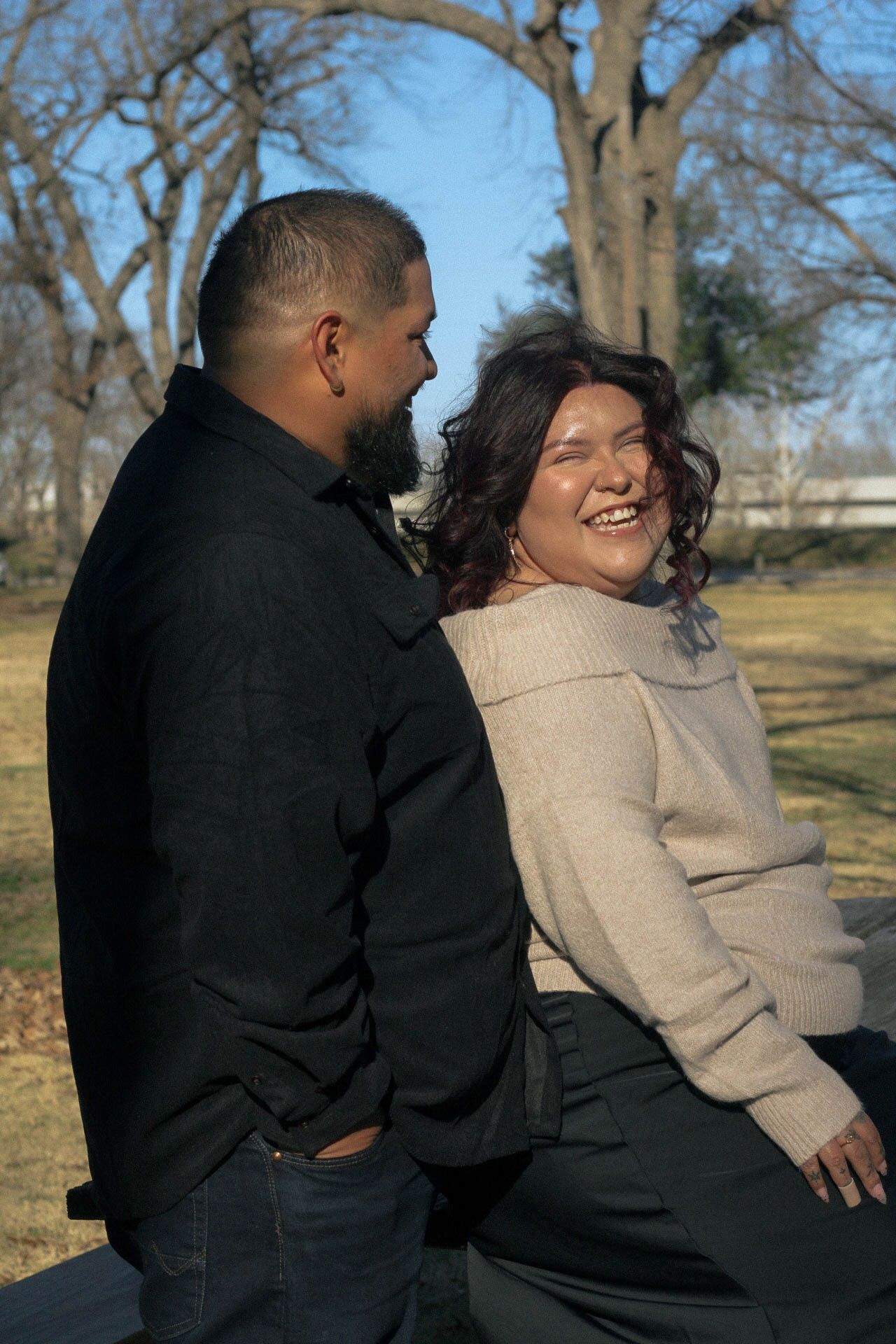 A joyful outdoor moment between a couple wearing contrasting dark and light clothing.