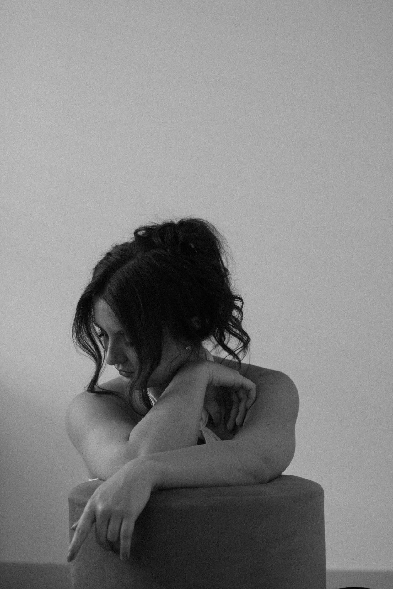 A person rests their head on their arms in a series of moody black and white photos.