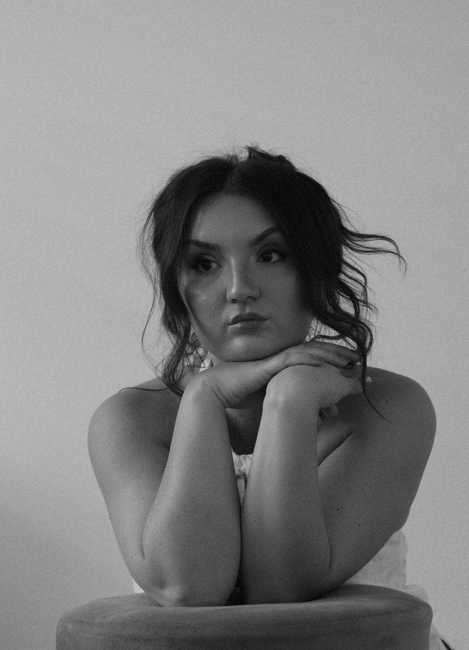 Artistic black and white portrait showing contemplative pose against light background.